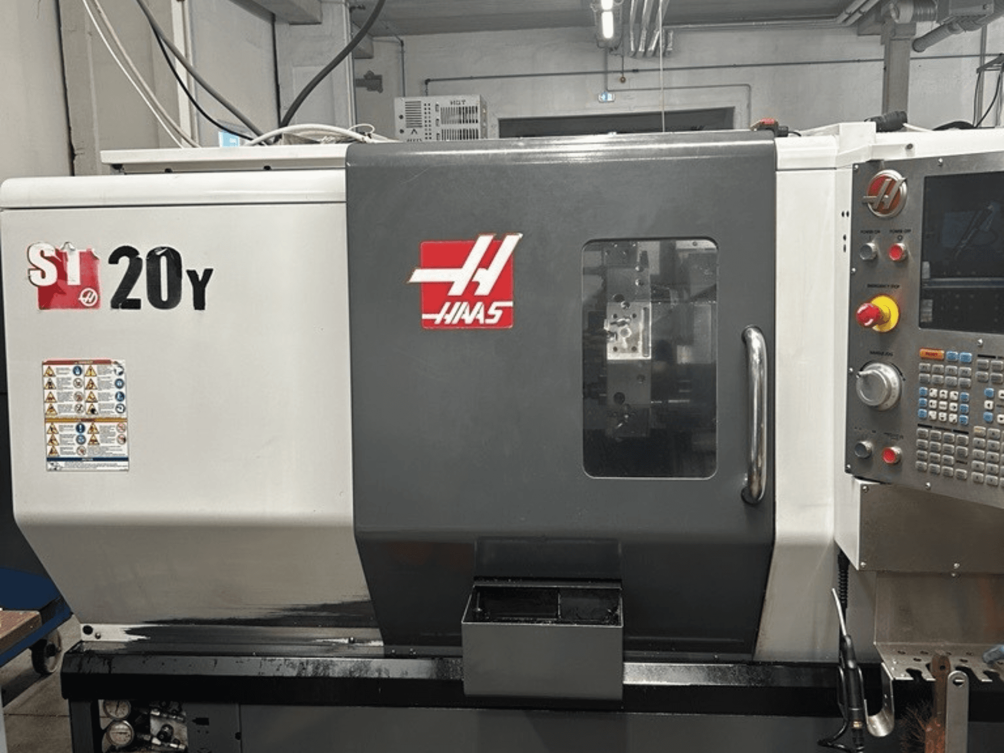 Haas ST-20Y CNC tokarilica, prednji pogled, prikazuje upravljačku ploču, sigurnosne naljepnice i operativni prozor.