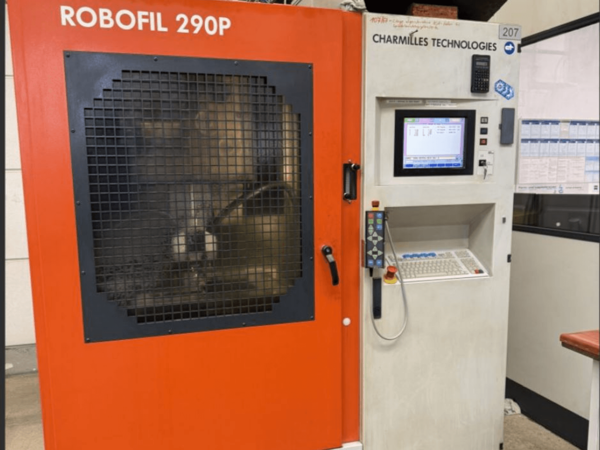 Prednji pogled na stroj za žičanu eroziju CHARMILLES TECHNOLOGIES Robofil 290P s upravljačkom pločom i radnim područjem zaštićenim mrežom.