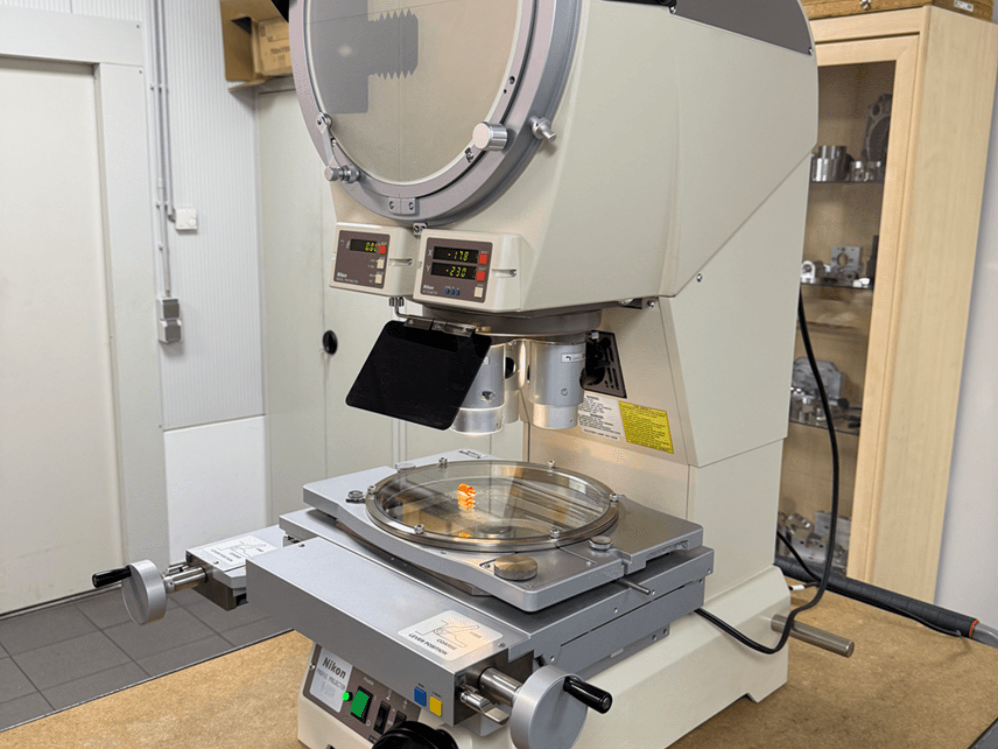 Nikonov model mikroskopa s prednje strane, s digitalnim zaslonima, podesivim stolićem i okruglom staklenom pločom.