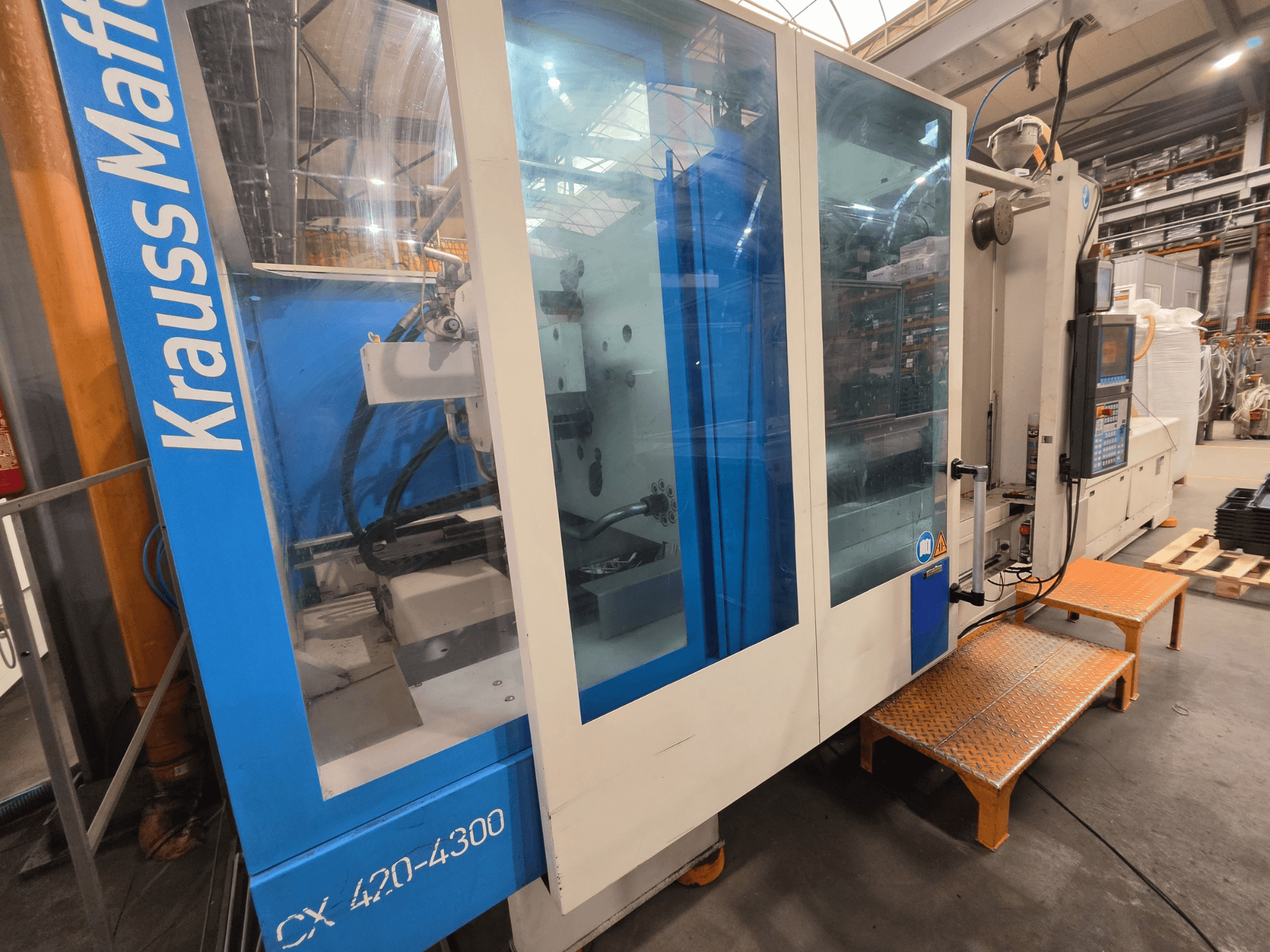 Krauss Maffei CX 420-4300 hidraulički stroj za brizganje plastike, bočni pogled, prikazuje upravljačku ploču i prozirne panele.