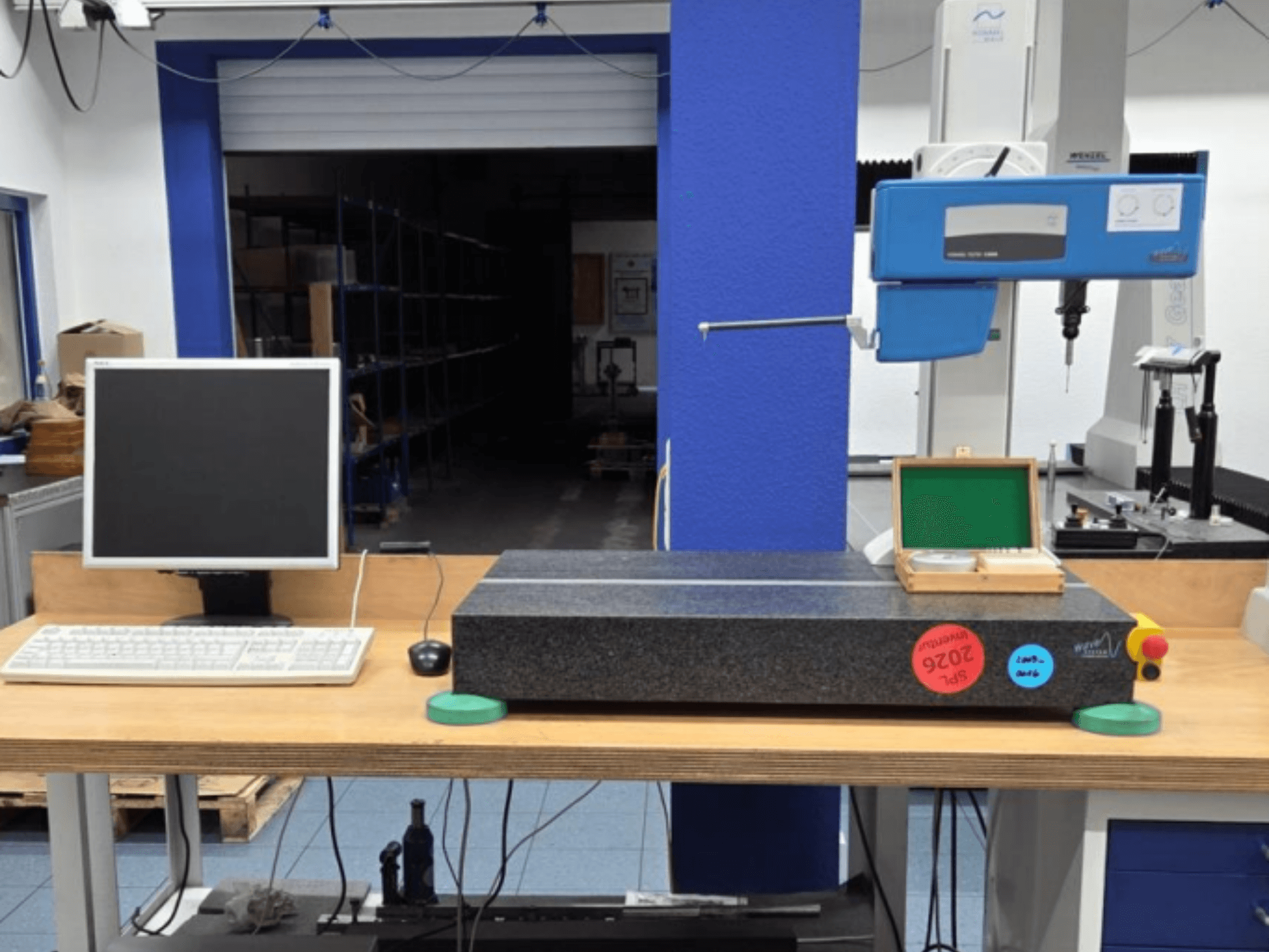 JENOPTIK wave C8000 CMM u radionici, s monitorom, tipkovnicom i granitnom mjernom površinom. Pogled sprijeda.