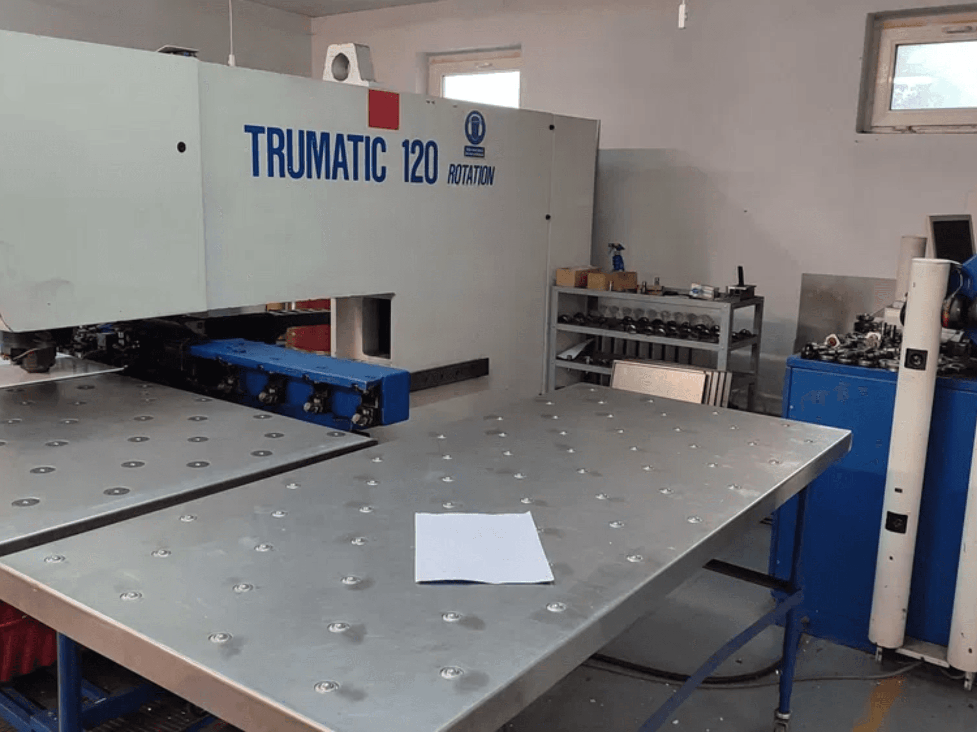 TRUMPF TRUMATIC 120R CNC stroj za probijanje, pogled sprijeda, s metalnim stolom s izbušenim rupama i praznim listom.