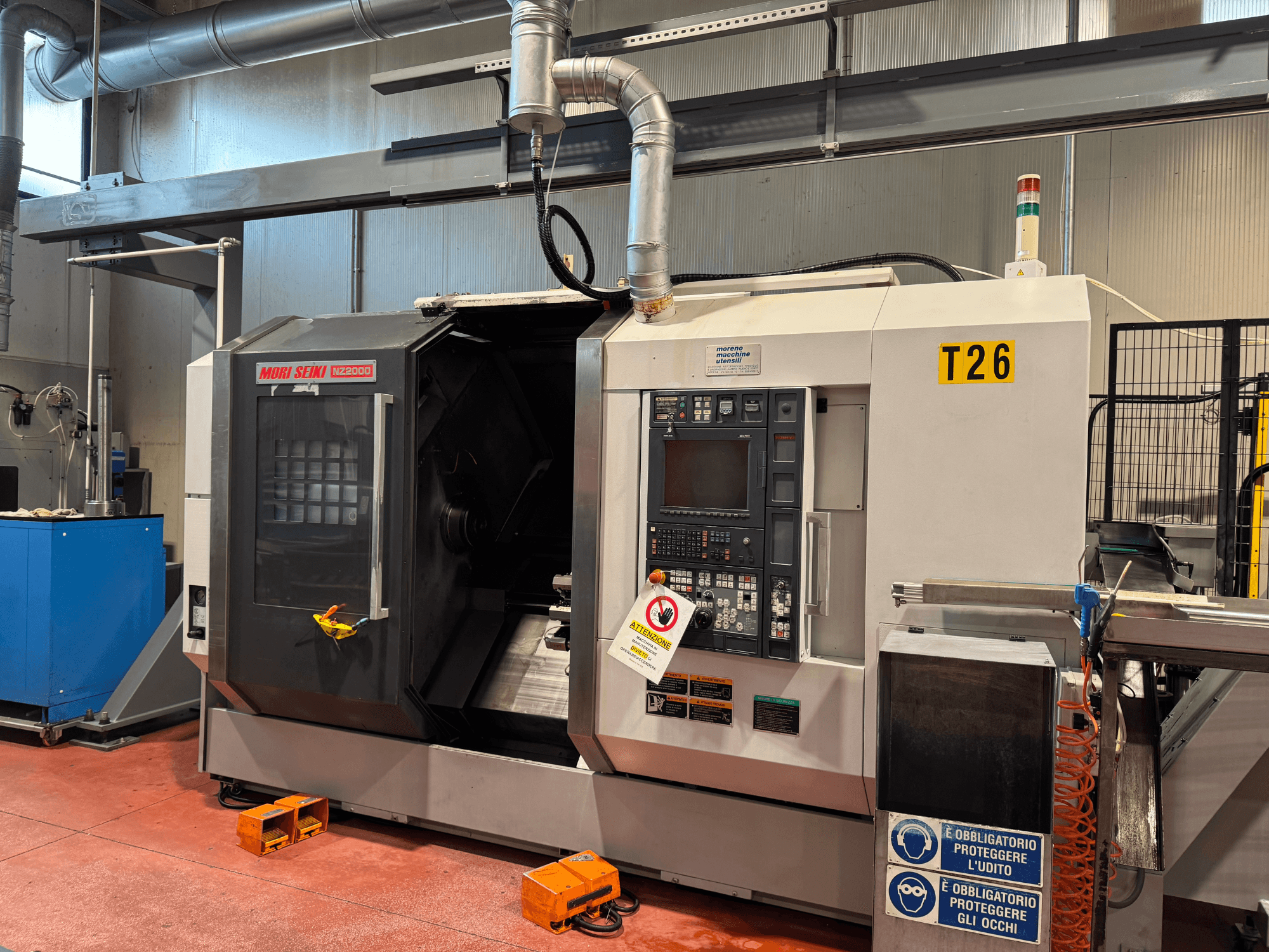 MORI SEIKI NZ-2000/T2/Y2 tokarsko-glodački centar, pogled sprijeda, sadrži upravljačku ploču, sigurnosne znakove i industrijsku konfiguraciju.