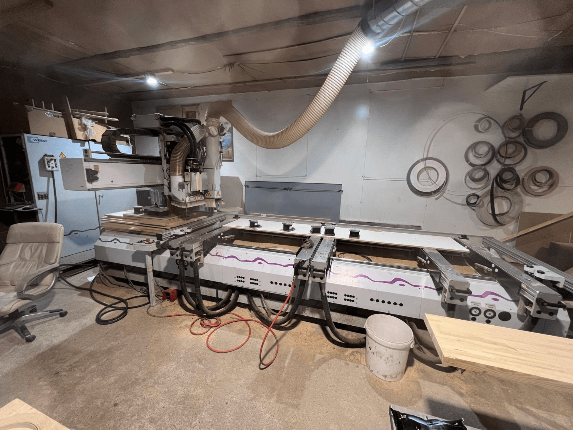 CNC centar za obradu drva Weeke OPTIMAT BP 120 u radionici, prednji pogled s drvenim komadima i alatima vidljivim na površini.