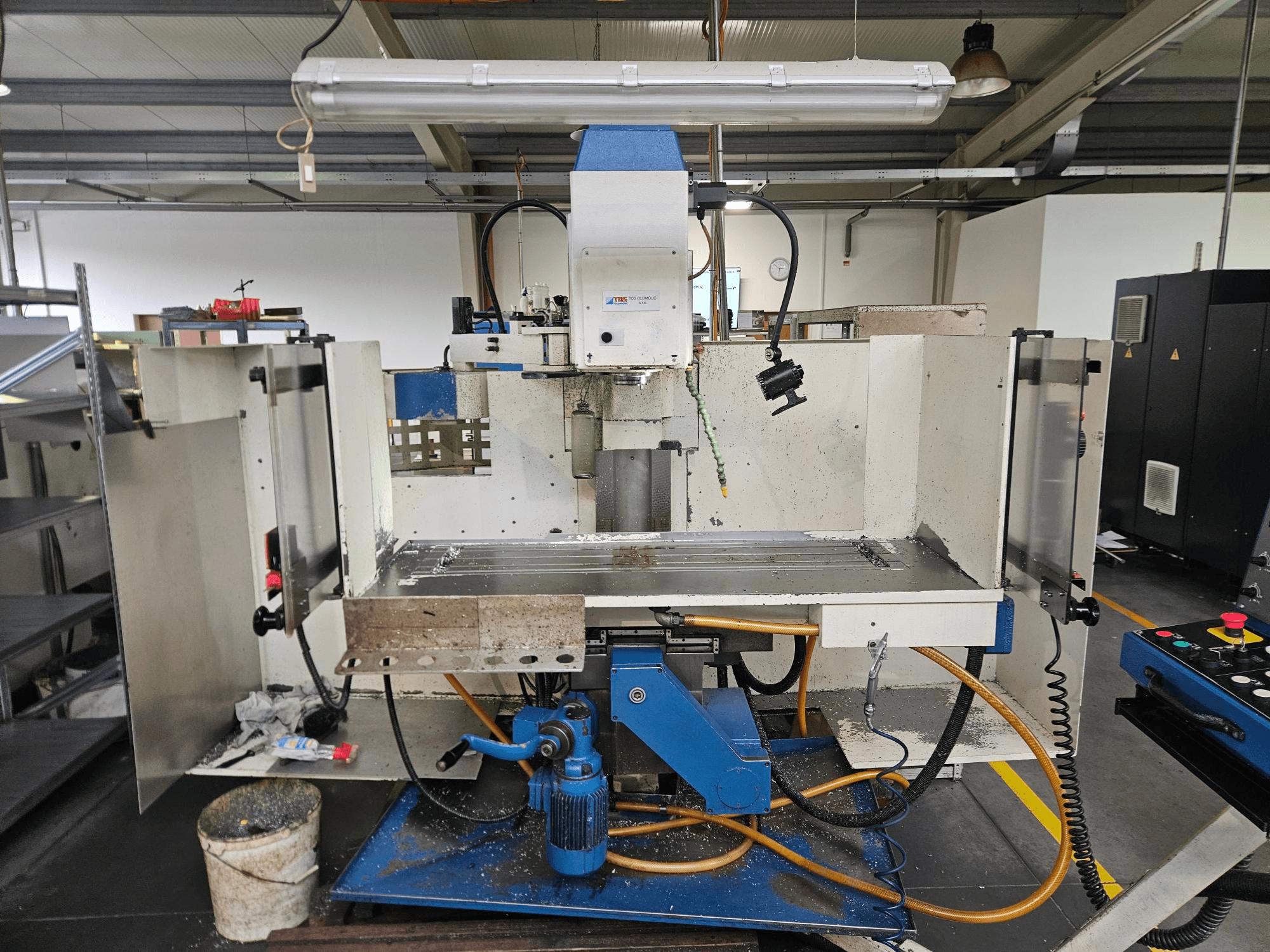 TOS Olomouc FV30 CNC Vertikalni obradni centar u radionici, prednji pogled koji prikazuje upravljačku ploču, radni stol i sustav rashladnog sredstva.