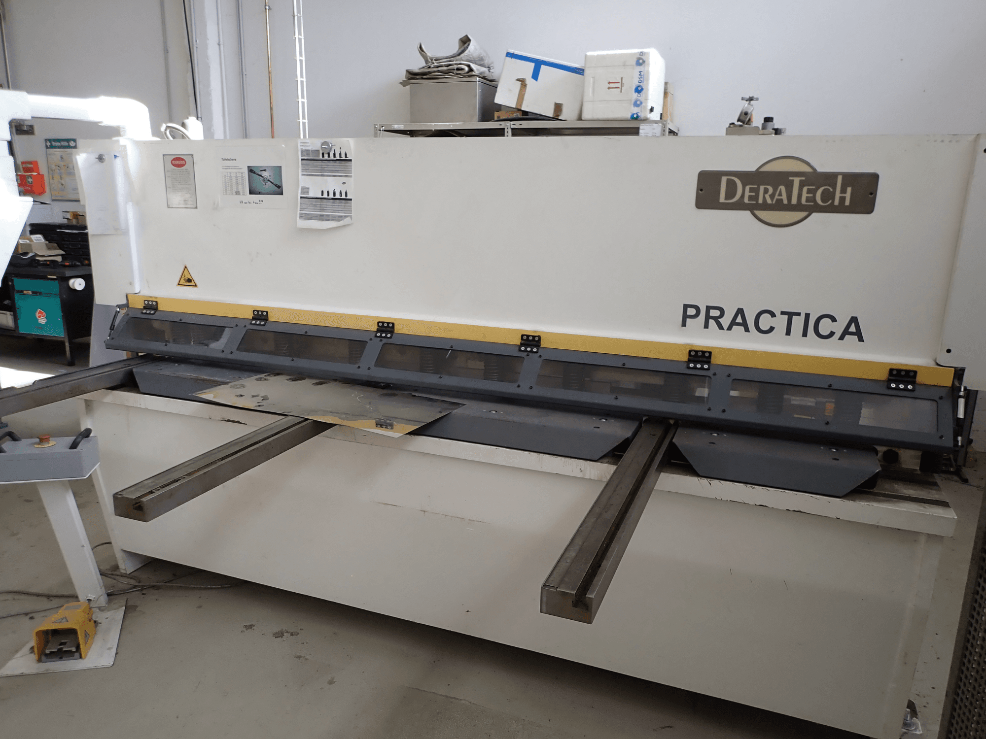 DERATECH Practica CNC škare, prednji pogled, s oštricom za rezanje i metalnim limovima na radnoj površini.