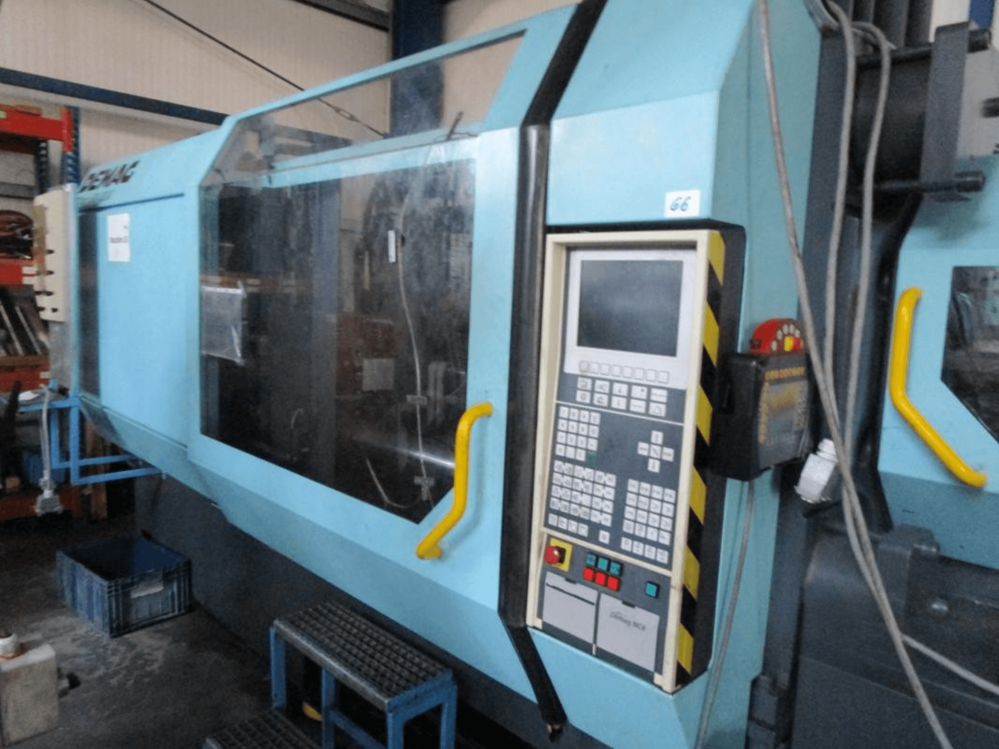 Demag Erdotech 500-3300 hidraulični stroj za brizganje plastike, prednji pogled, ima upravljačku ploču i prozirno sigurnosno kućište.