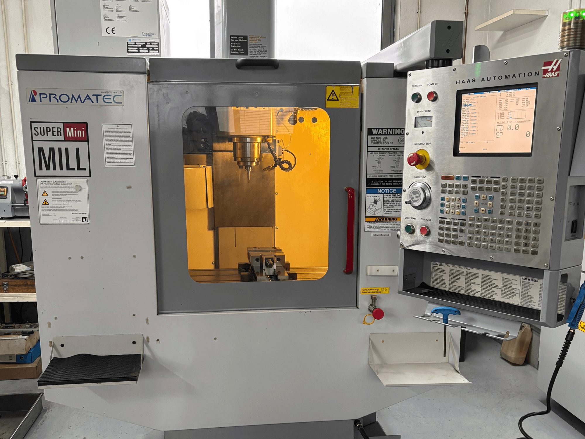 Promatec Super Mini Mill u prednjem pogledu, opremljen Haas Automation upravljačkom pločom i vidljivim alatom za rezanje unutra.