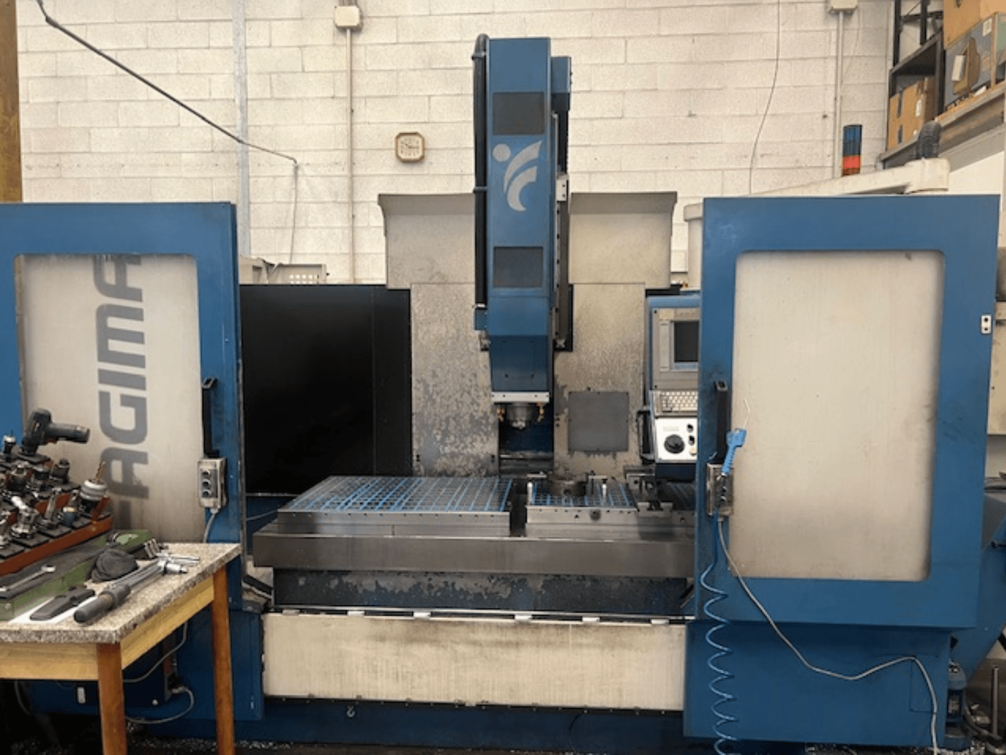 Prednji pogled na JAGIMA CNC stroj s velikim metalnim radnim prostorom, vidljivom upravljačkom pločom i alatima na obližnjem stolu.