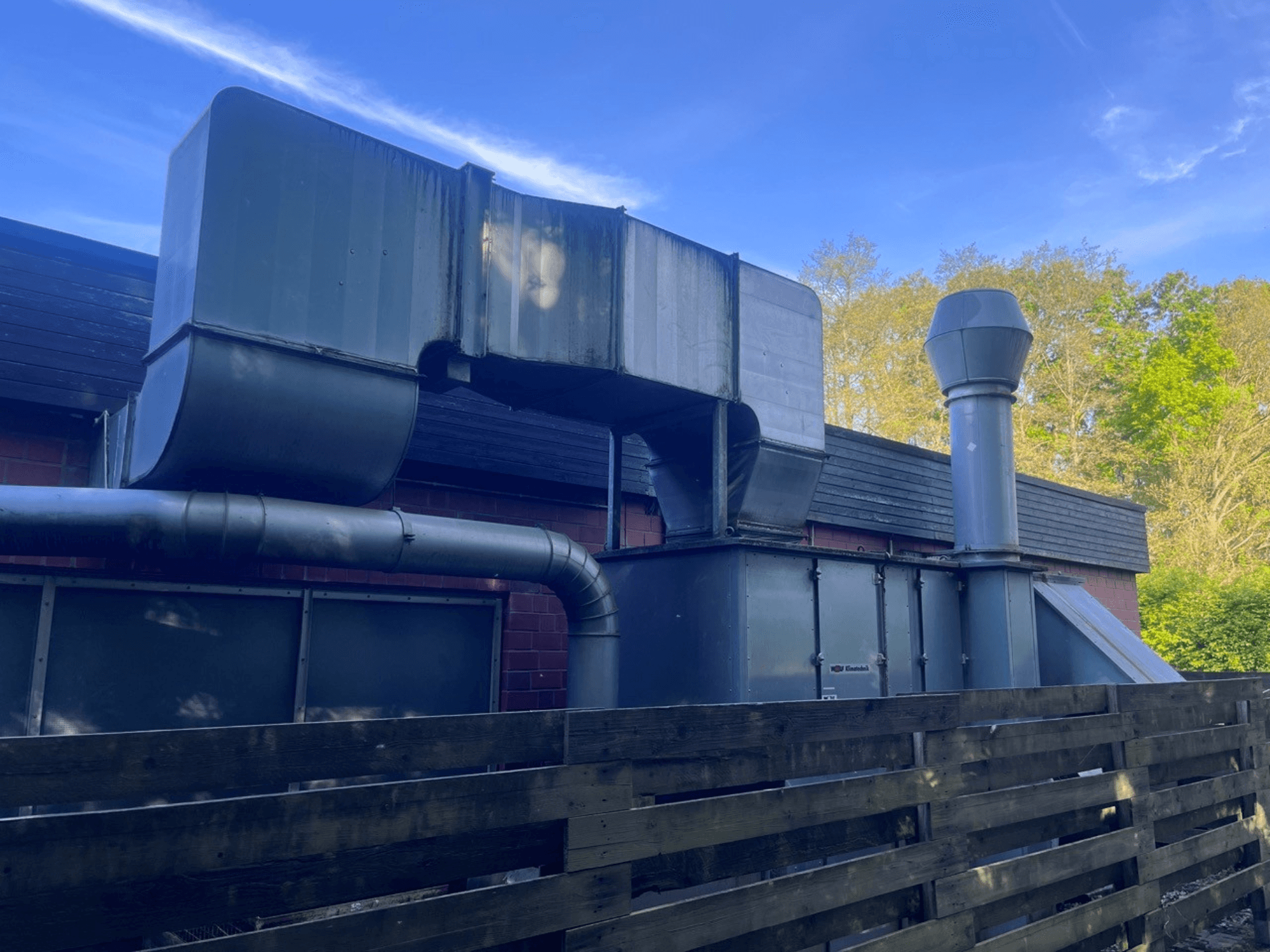 Industrijski ventilacijski sustav s metalnim kanalima, bočni pogled; uključuje kvadratni i cilindrični dimnjak, zelene boje.