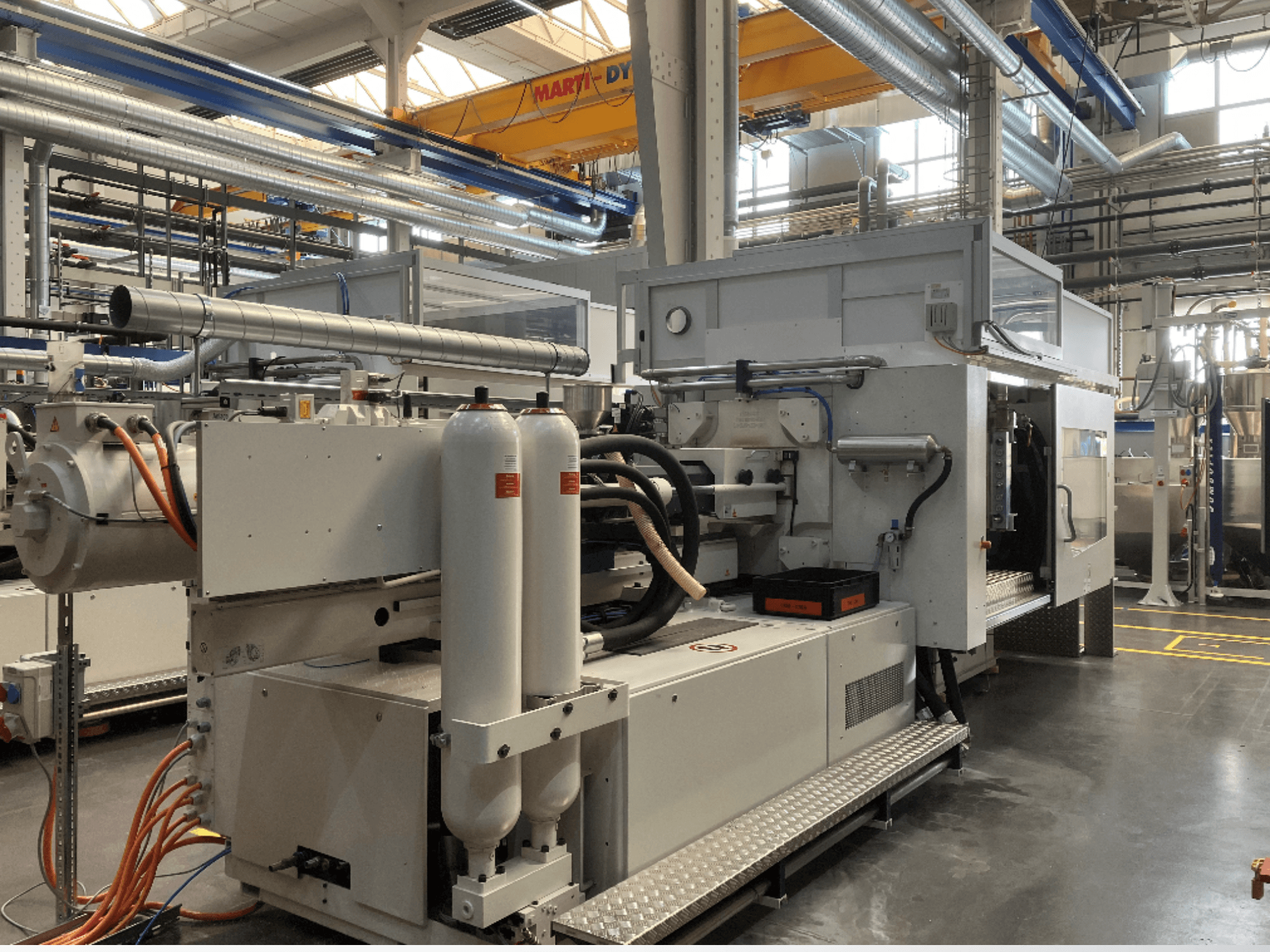 Industrijski stroj prikazan u bočnom pogledu s više crijeva, dva vertikalna spremnika i upravljačkom pločom; marka/model nisu vidljivi.