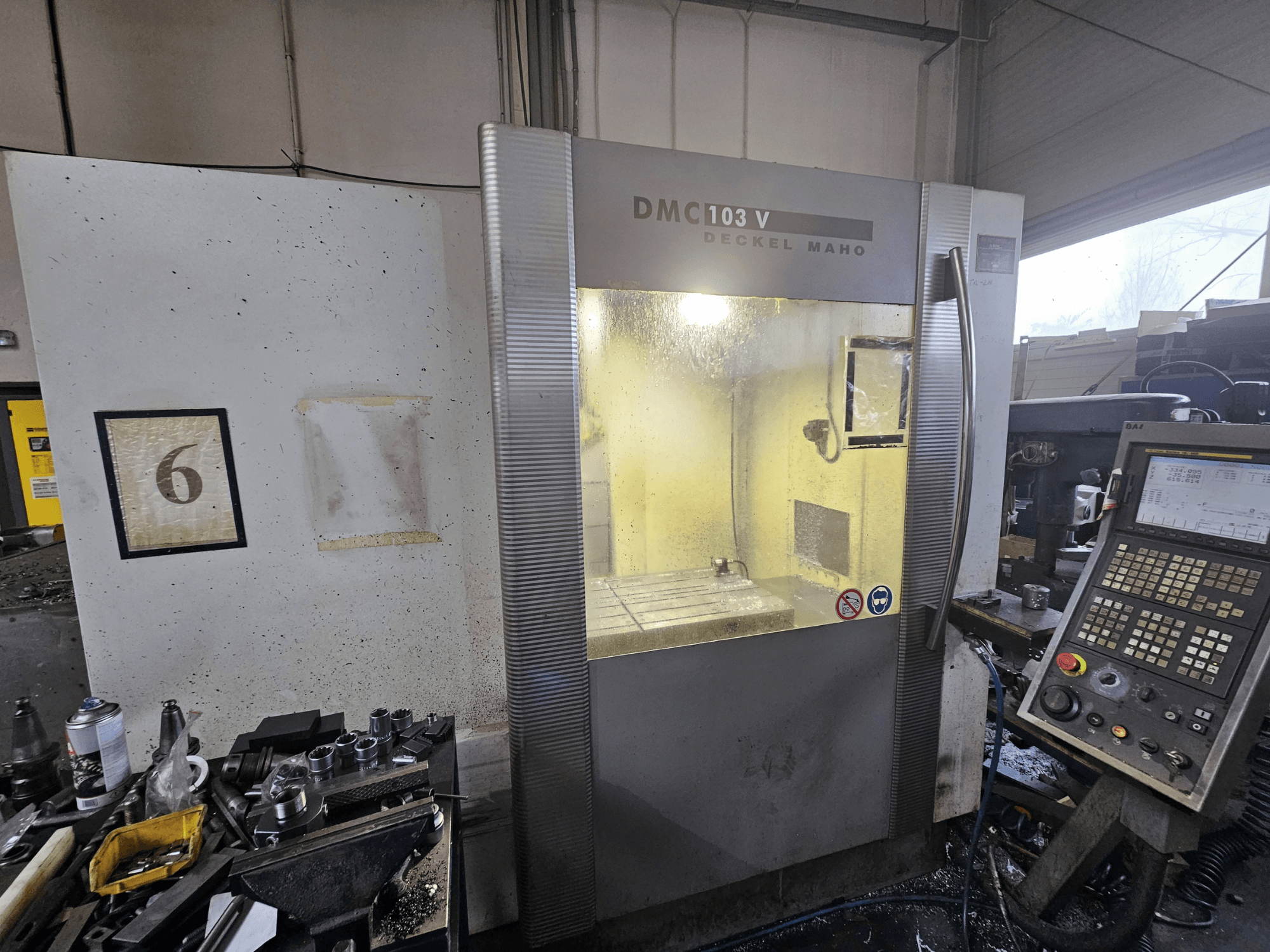 Prednji pogled na CNC stroj Deckel Maho DMC 103 V, s upravljačkom pločom, radnim područjem i numeriranim indikatorom "6".