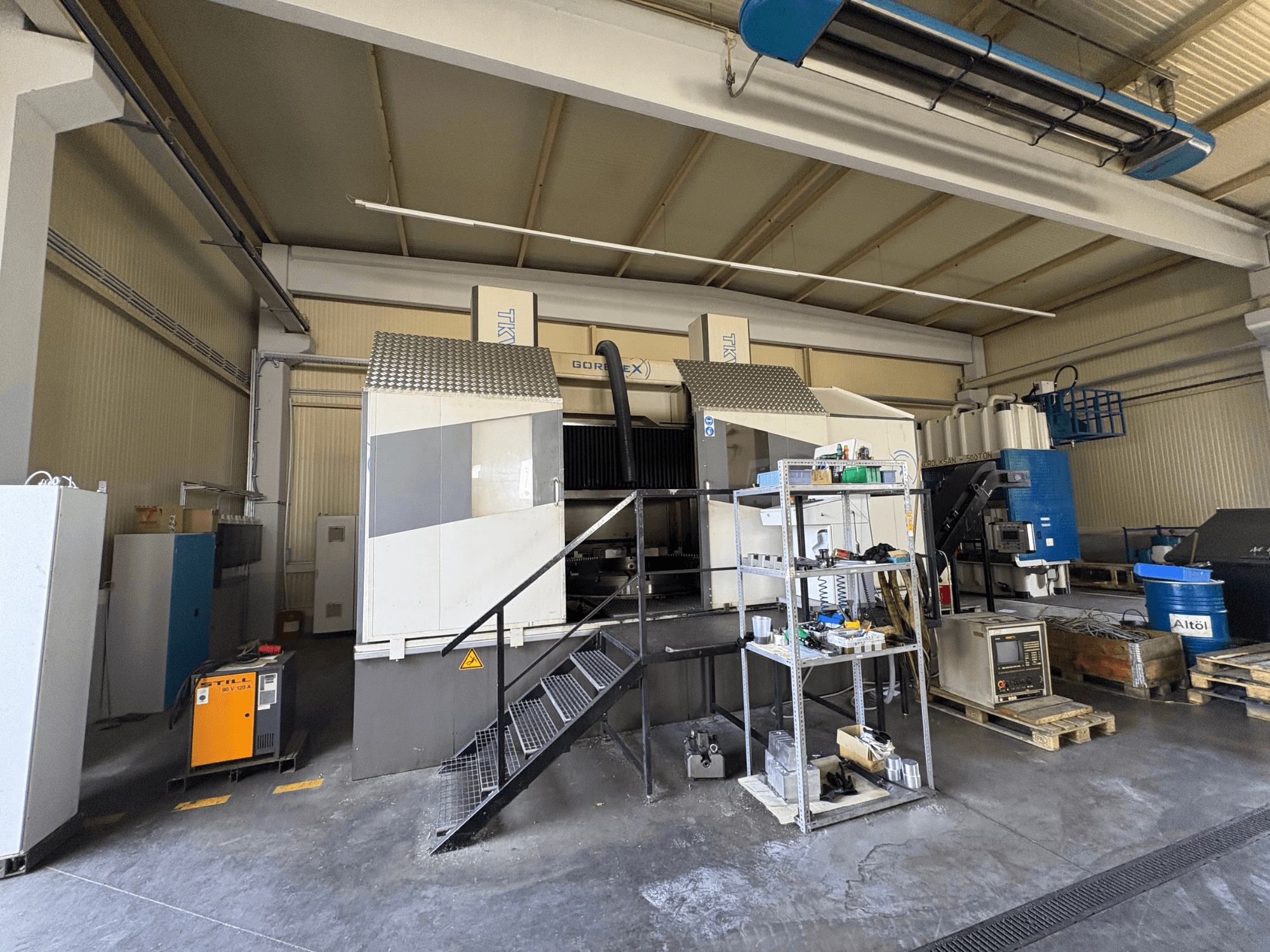 Industrijski strojni postav s GORAT X strojem, bočni pogled; uključuje alate, upravljačku ploču i opremu na policama.