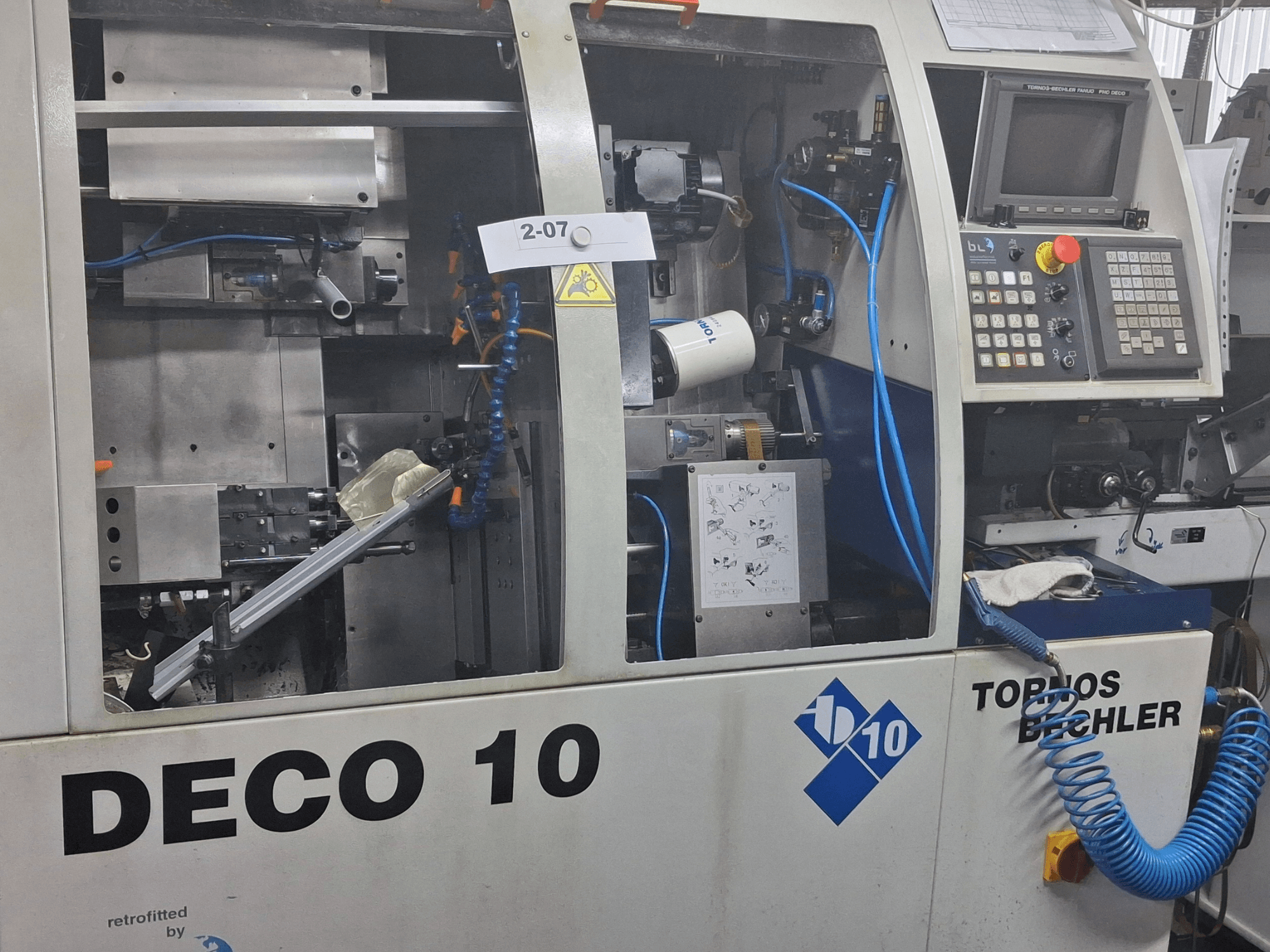 Pogled izbliza na tokarski stroj TORNOS Deco 10a švicarskog tipa, s prikazom unutarnjeg mehanizma i detalja upravljačke ploče.