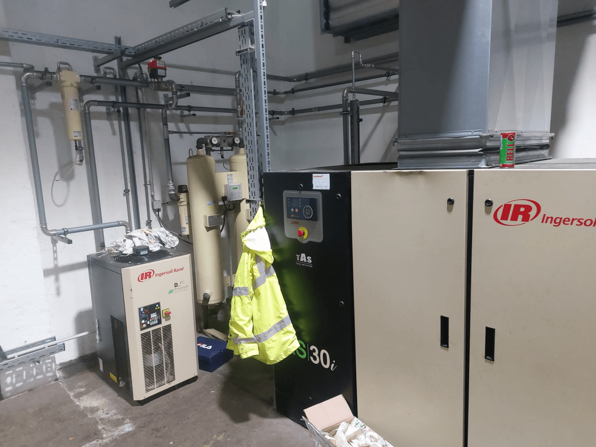 Ingersoll Rand D480EC-A alatni stroj u radionici, bočni pogled s cijevima, upravljačkim elementima i žutim sigurnosnim prslukom u blizini.
