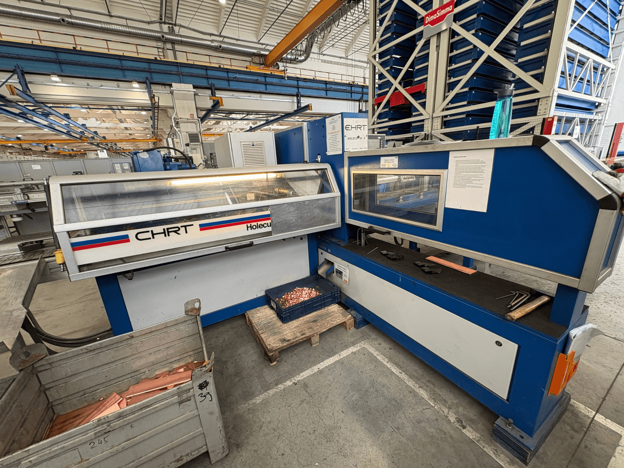 CNC stroj za probijanje EHRT Holecut 40-9, prednji pogled, s upravljačkom pločom, metalnim spremnikom i bakrenim limovima u blizini.