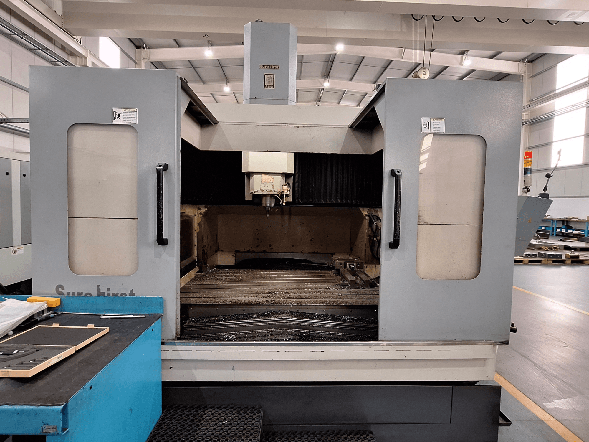 Vertikalni obradni centar Sure First QM-1836, prednji pogled koji prikazuje glavu alata i prazno radno područje, moderno industrijsko okruženje.