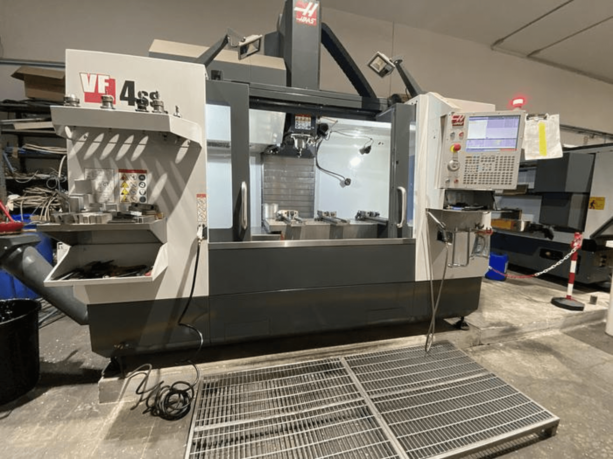 Haas VF-4SS CNC glodalica, prednji pogled, sa spremištem za alat, upravljačkom pločom i vidljivim radnim prostorom u radioničkom okruženju.