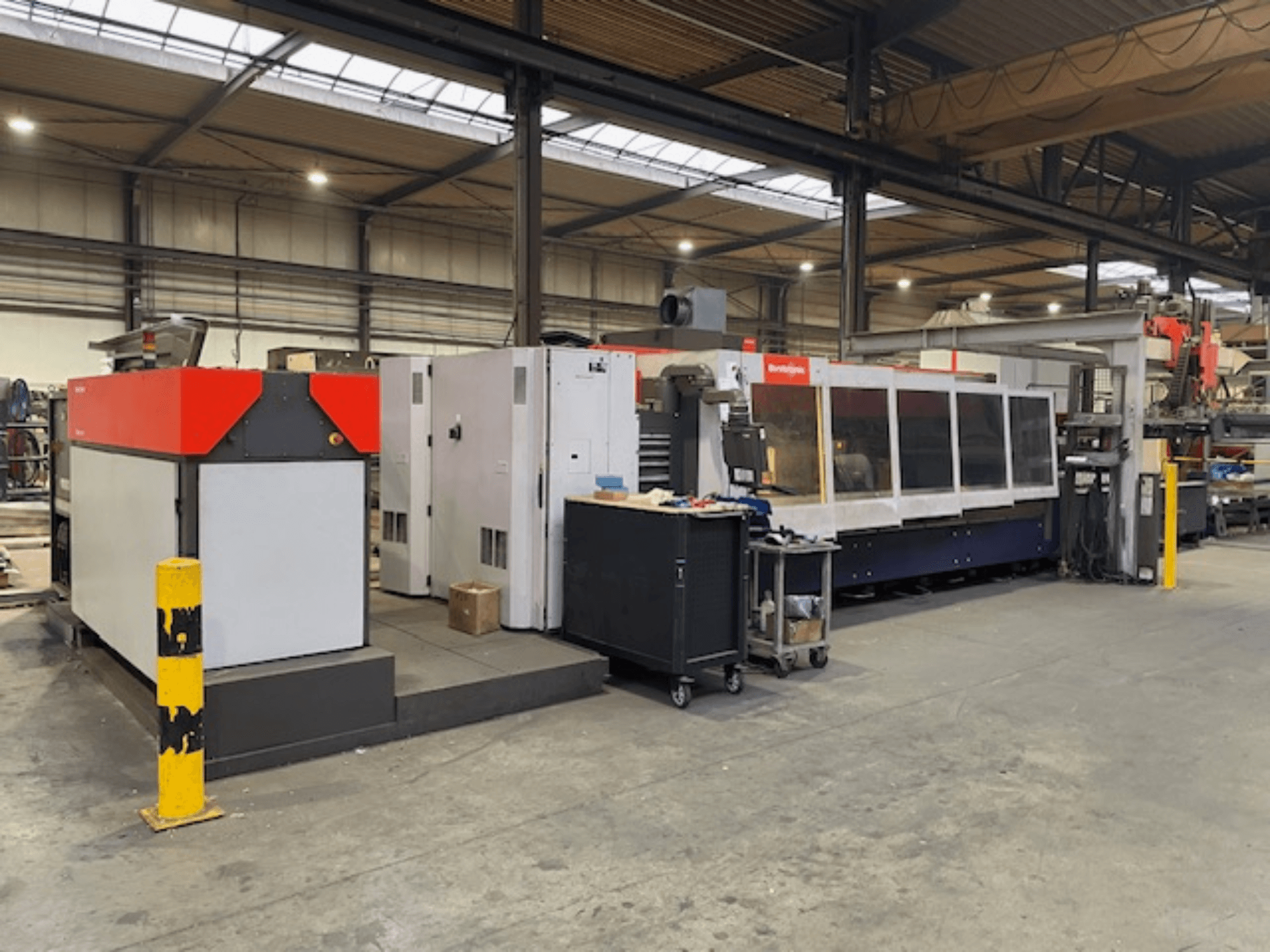 Stroj za rezanje CO2 laserom Bystronic BySpeed 3015, bočni pogled u radionici, s prepoznatljivim crvenim i sivim dizajnerskim elementima.