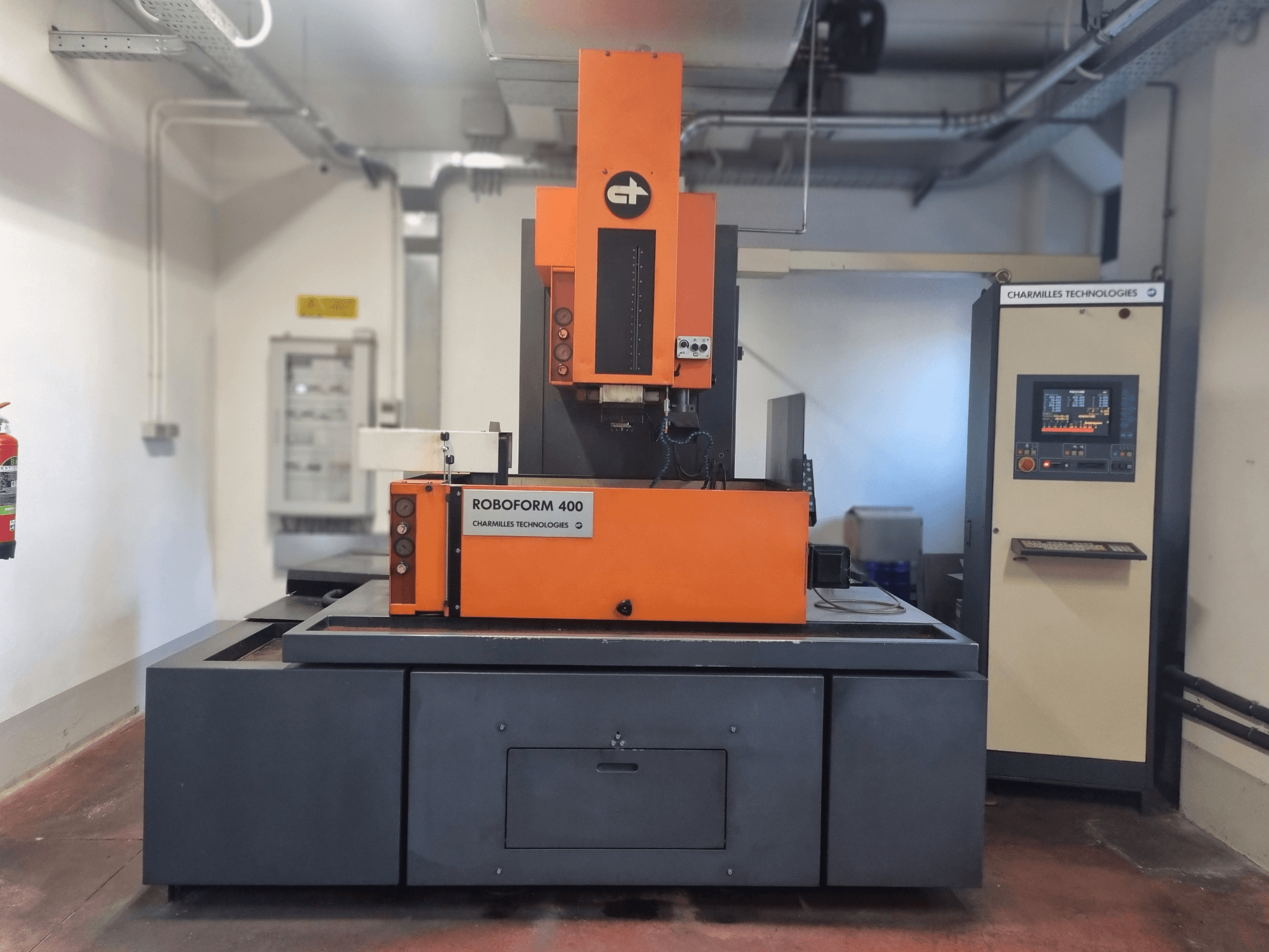 Stroj Roboforn 400 tvrtke Charmilles Technologies, pogled sprijeda, narančasto-sivog dizajna, vidljiva digitalna upravljačka ploča.