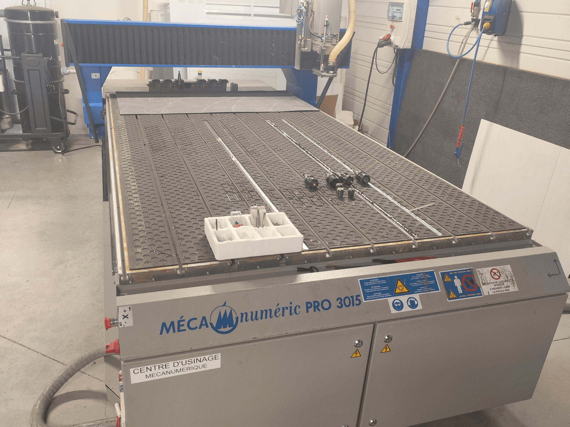 CNC glodalica MECANUMERIC Pro 3015, prednji pogled, s detaljnim reznim postoljem, upravljačkom pločom i priborom na stolu.