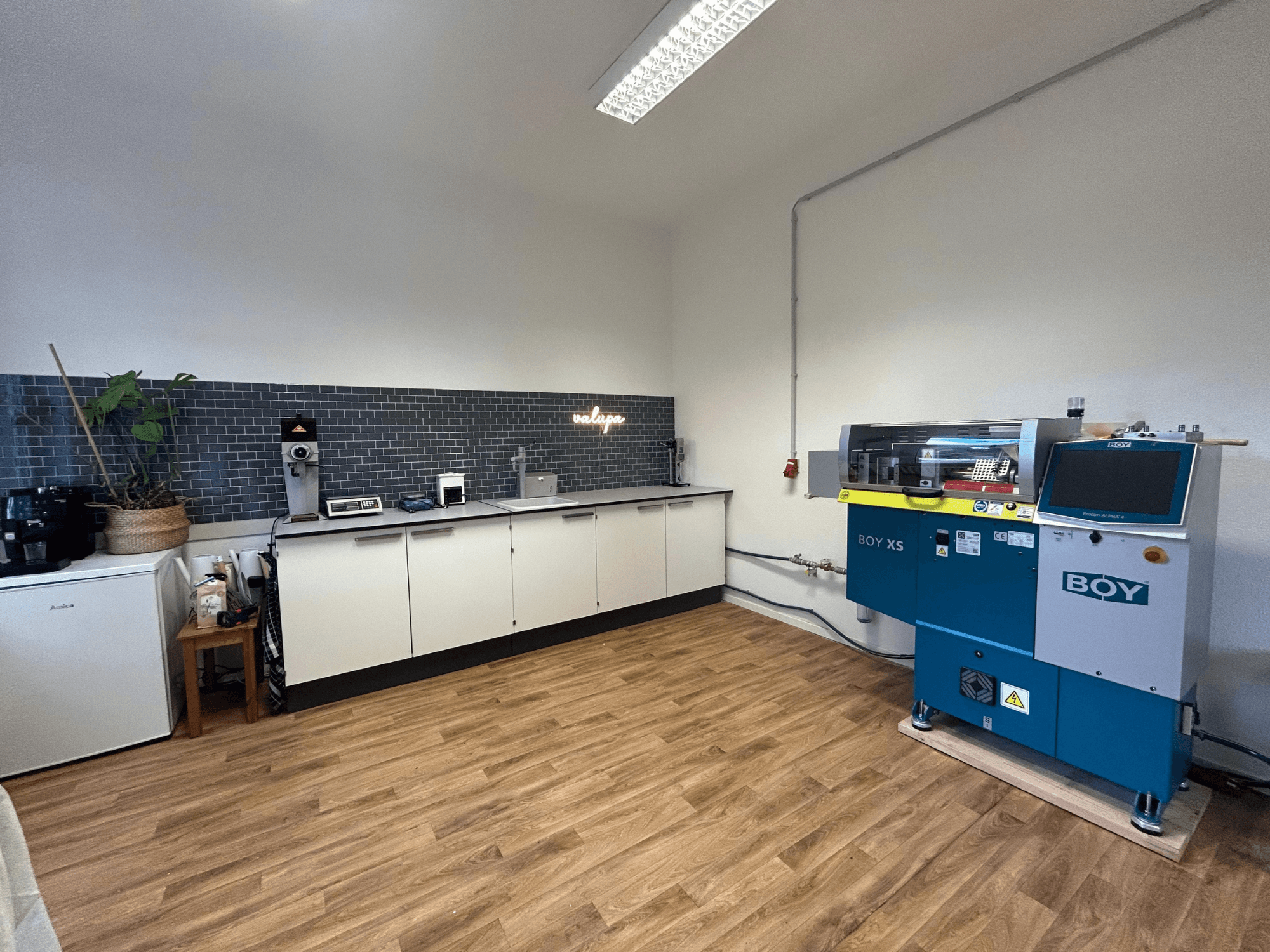 Hidraulički stroj za brizganje plastike BOY XS 161, prednji pogled, u modernom kuhinjskom okruženju s aparatima i drvenim podovima.