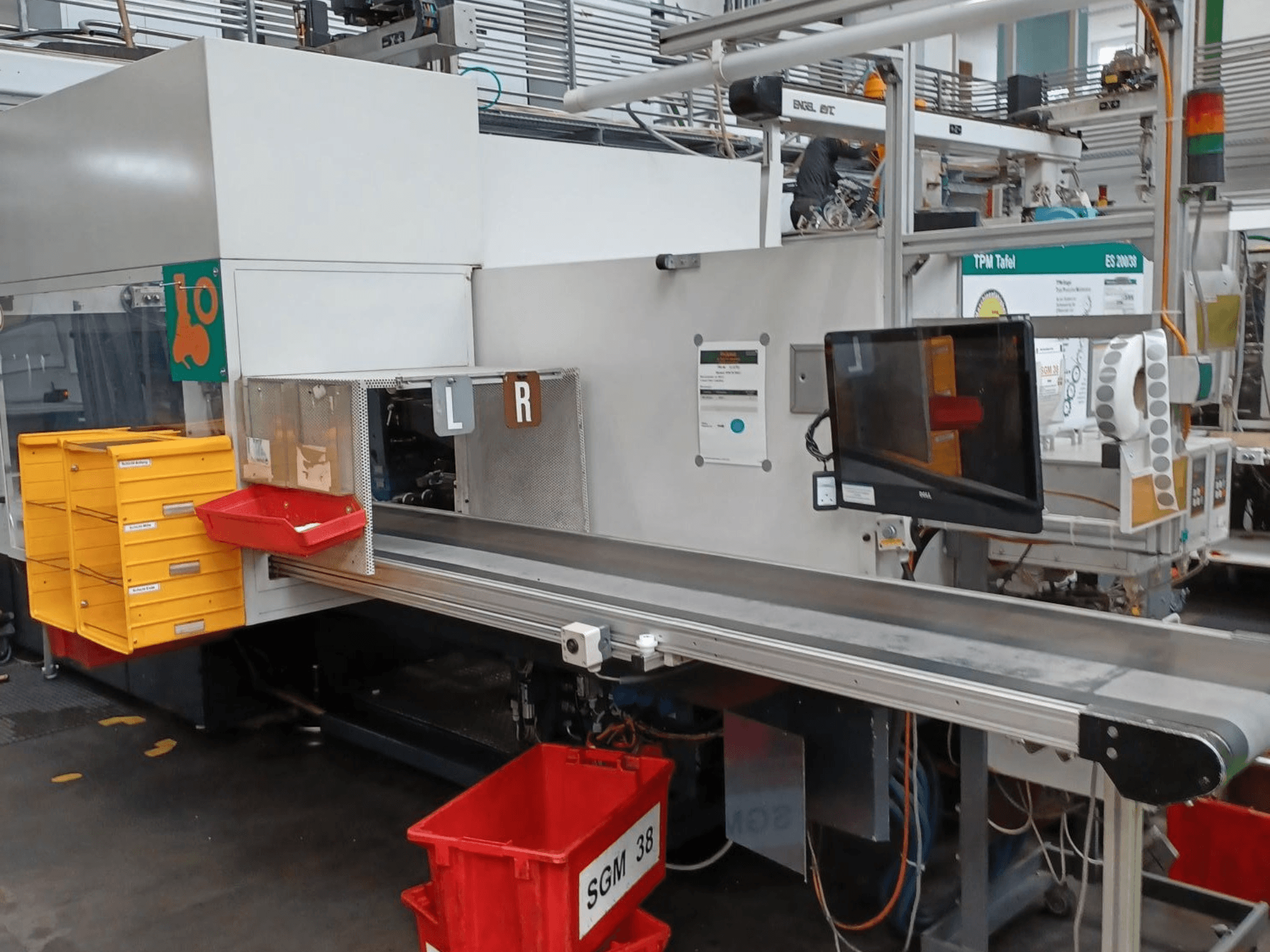 Industrijski stroj za sortiranje sa žutim i crvenim spremnicima, bočni pogled, s upravljačkim monitorom i označenim odjeljcima za sortiranje.