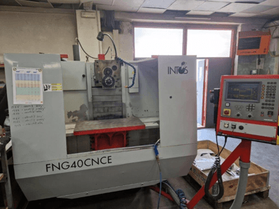 INTOS FNG40CNC stroj, prednji pogled, sadrži upravljačku ploču, operativne dijelove i metalni radni stol. Idealan za strojnu obradu.