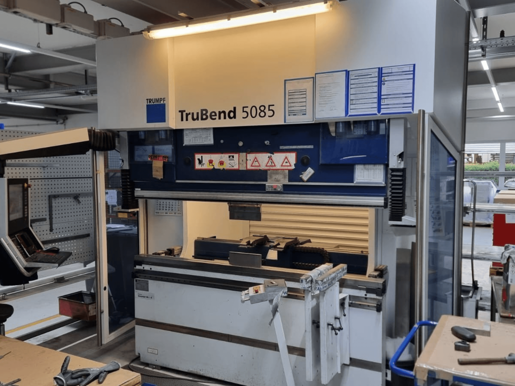 TRUMPF TruBend 5085 stroj za savijanje, prednji pogled, prikazuje upravljačku ploču, radnu stanicu i sigurnosna upozorenja unutar radionice.