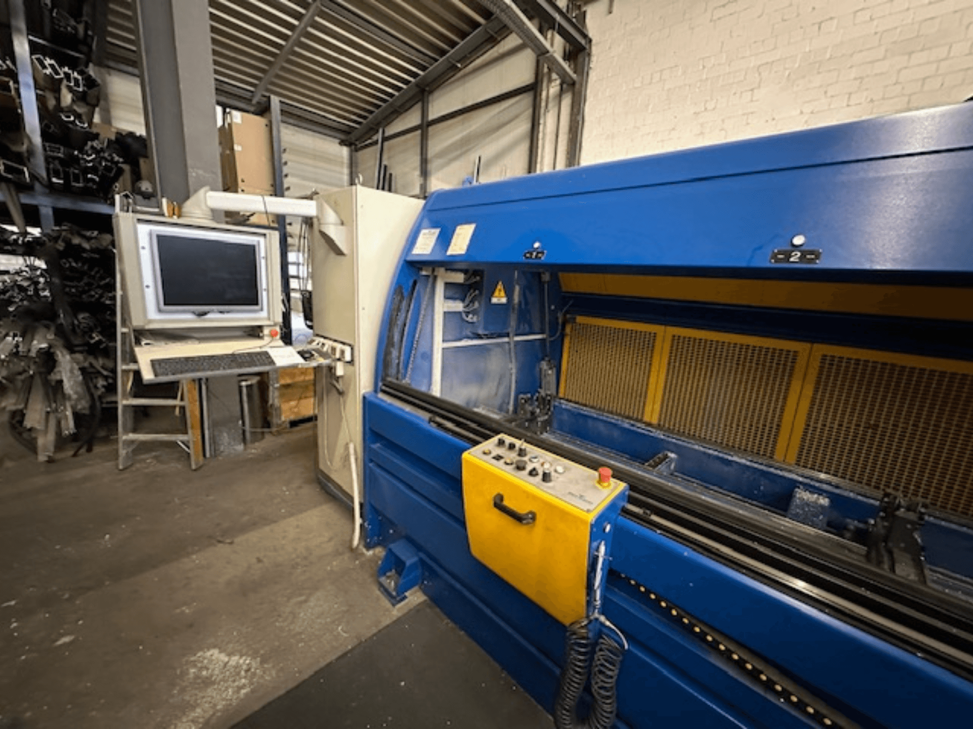 Prednji pogled na SCHÜCO Profilbearbeitungscenter 299 650, univerzalni obradni centar s upravljačkim elementima i računalnom radnom stanicom.