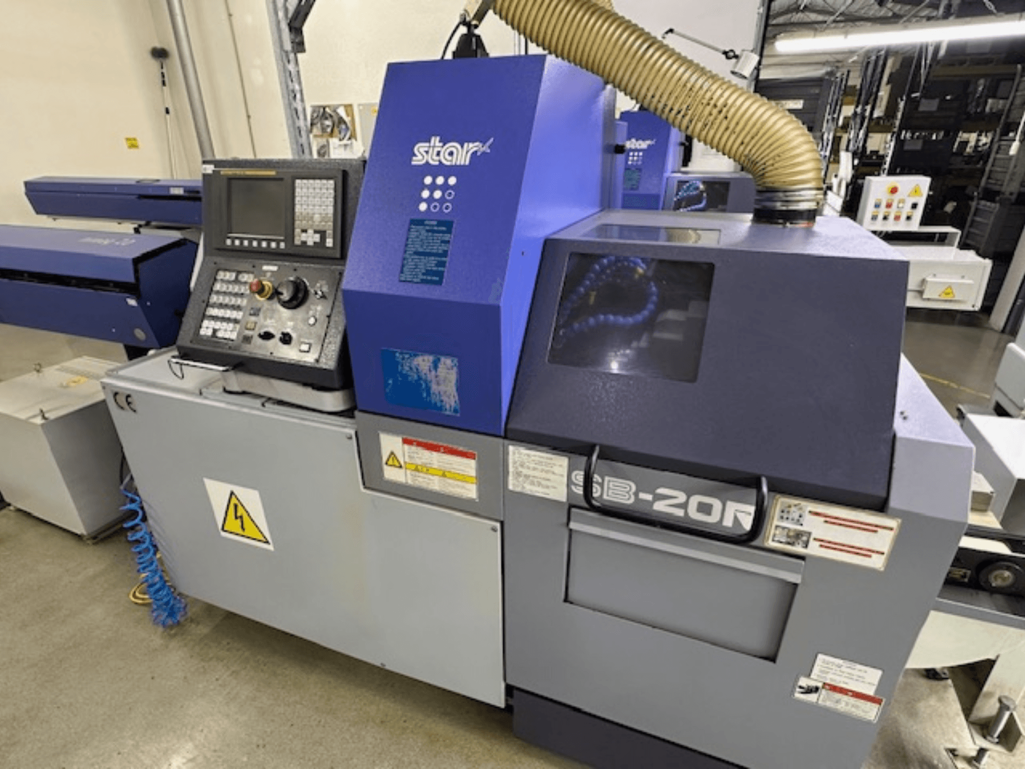 Tokarski stroj švicarskog tipa Star SB-20R tip N, prednji pogled, s upravljačkom pločom, usisnim crijevom i vidljivim simbolima opasnosti.