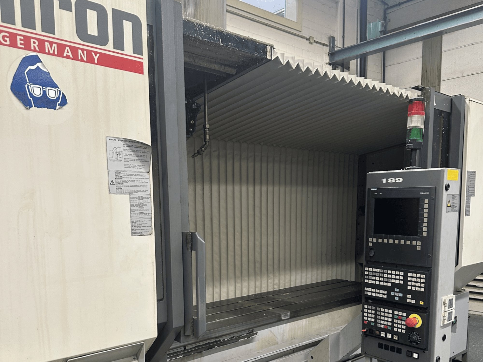 Alternativni tekst: Prednji pogled na Hermle CNC stroj s upravljačkom pločom koja prikazuje gumbe i zaslon, s otvorenim radnim područjem.