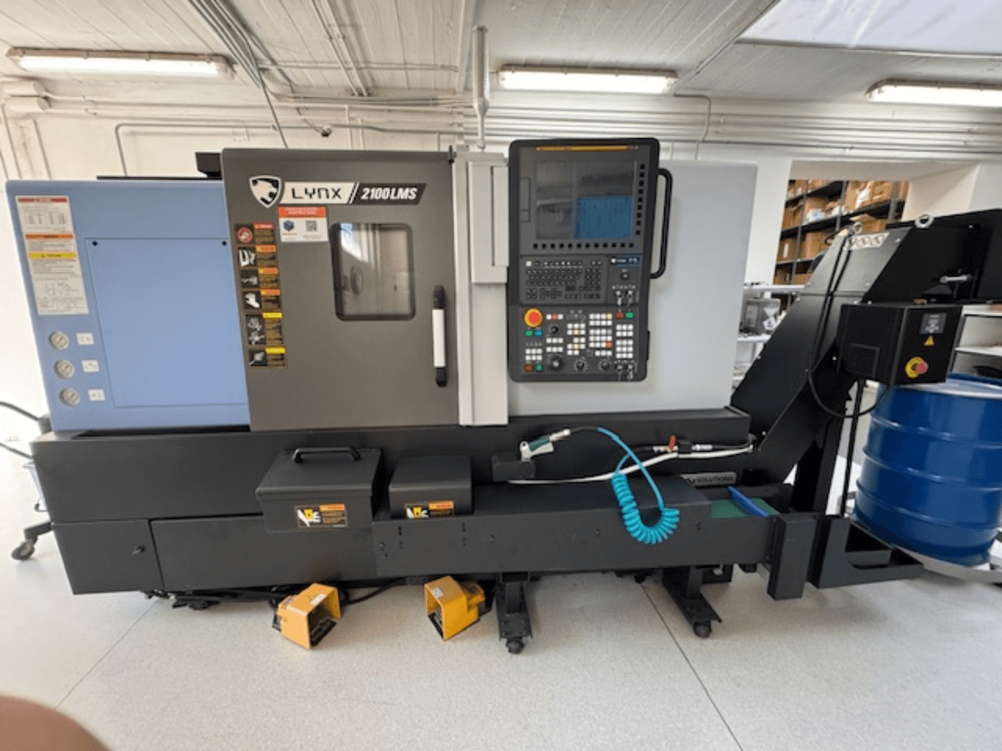 Horizontalni tokarski stroj DOOSAN LYNX 2100LMSA, prednji pogled, sadrži upravljačku ploču, crijevo za rashladnu tekućinu i kutije za pohranu.