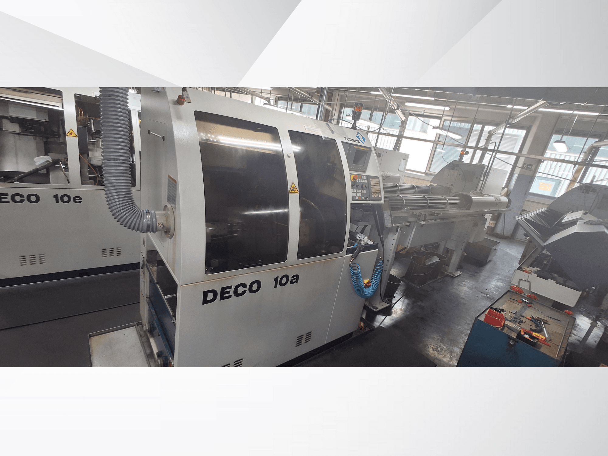 DECO 10a CNC stroj u radionici, s prednjim pogledom, upravljačkom pločom i ispušnim sustavom. Ima robusnu konstrukciju i precizne alate.