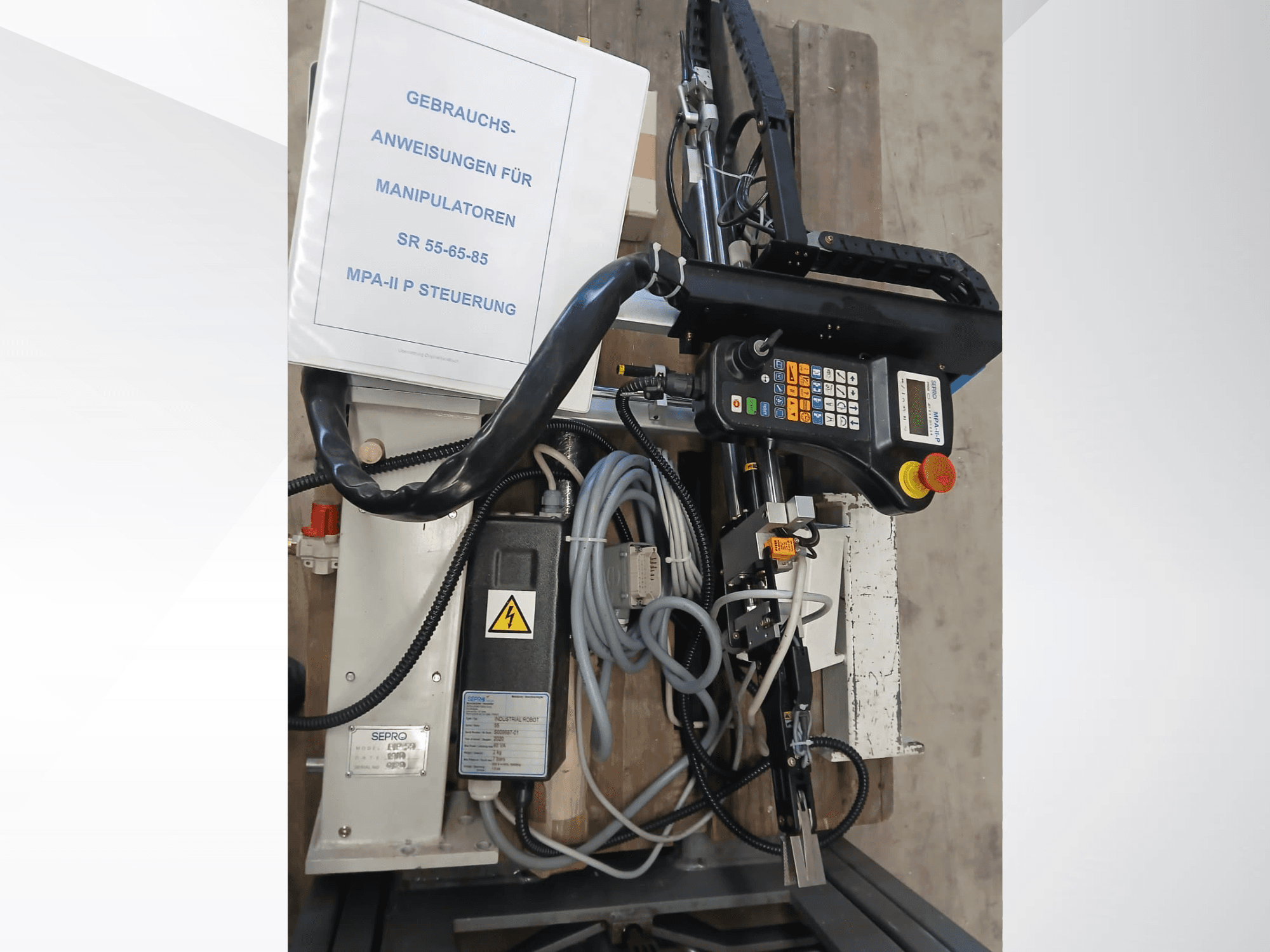 Upravljačka ploča i komponente portalnog robota Sepro PIP-55, gledano sa strane, s vidljivim korisničkim priručnikom.