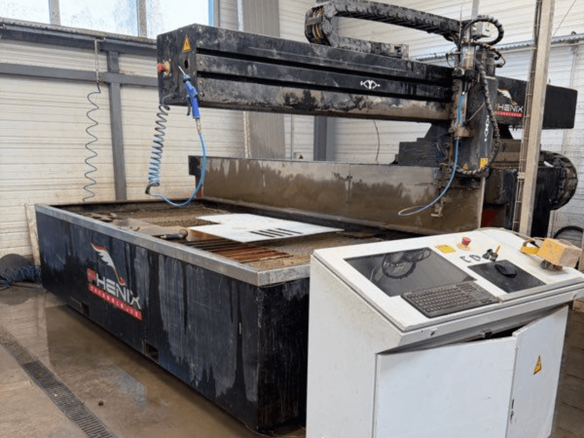 Stroj za rezanje vodenim mlazom PHENIX MD JET 1530, prednji pogled s upravljačkom pločom i područjem rezanja s vidljivim spremnikom za vodu.