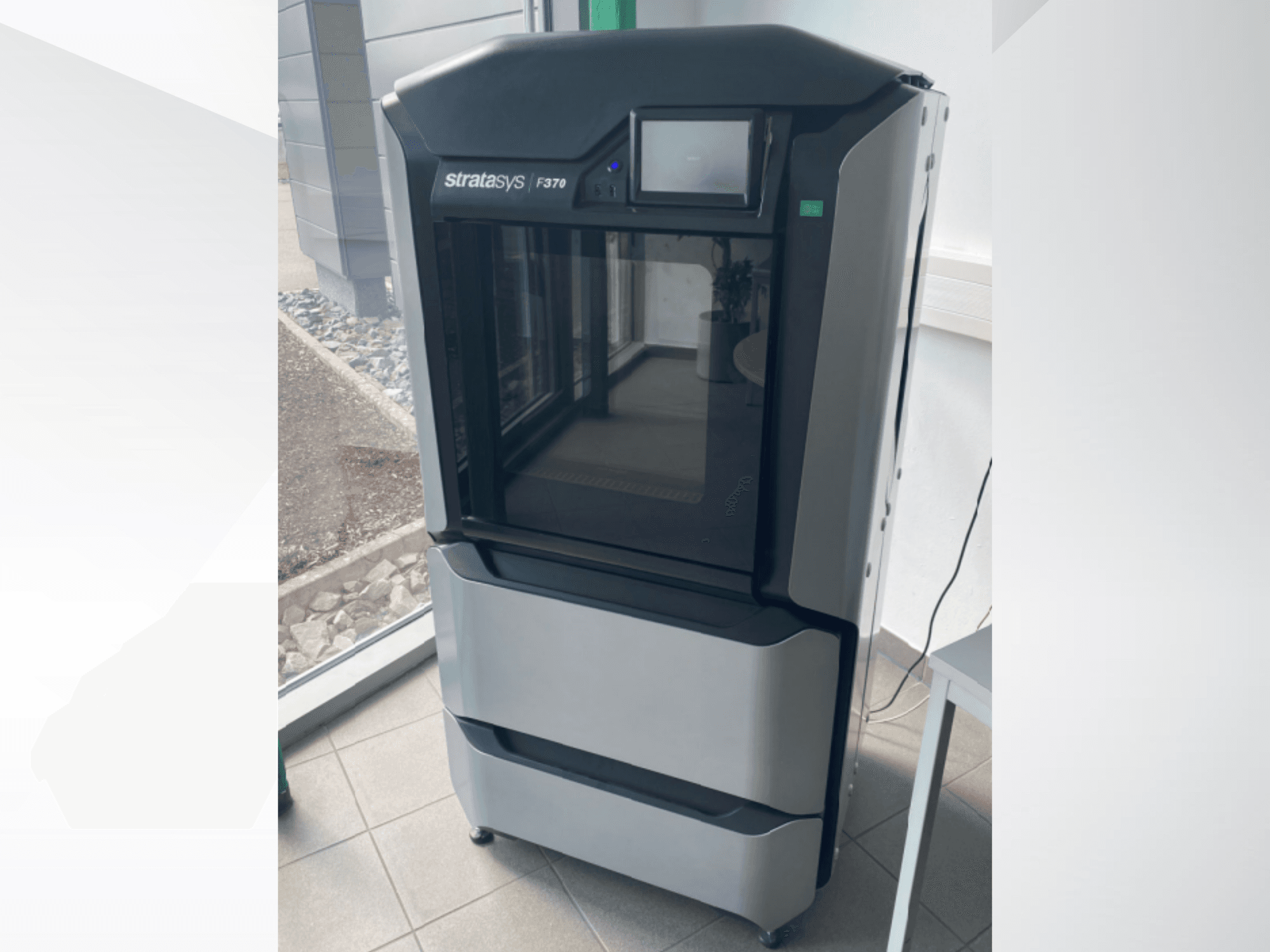 Plastični 3D printer Stratasys F370, prednji pogled, s elegantnim crno-sivim dizajnom i zaslonom osjetljivim na dodir.