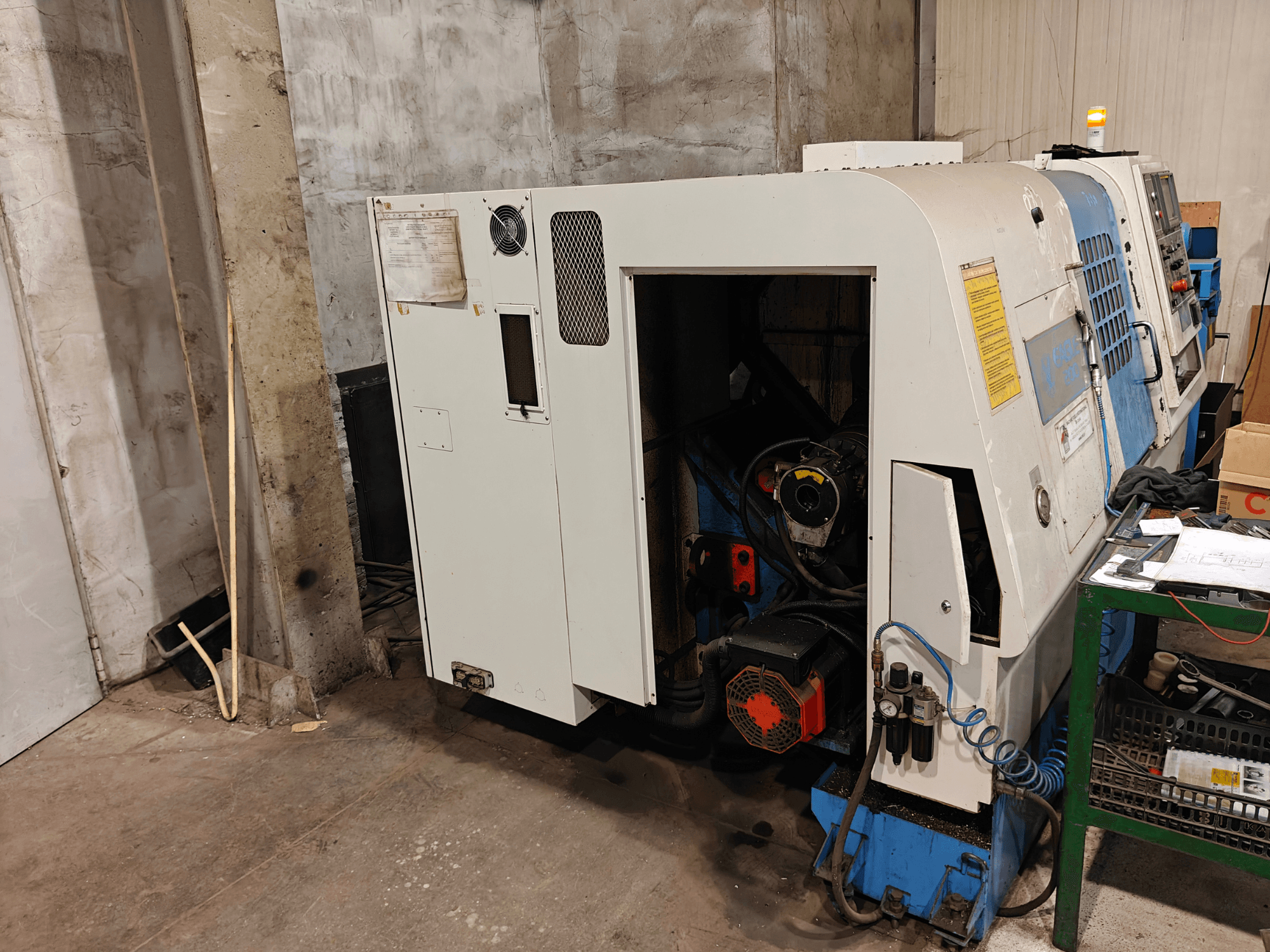 Prednji pogled na tokarski stroj, marka i model nisu navedeni, s upravljačkim elementima i vidljivim komponentama motora.