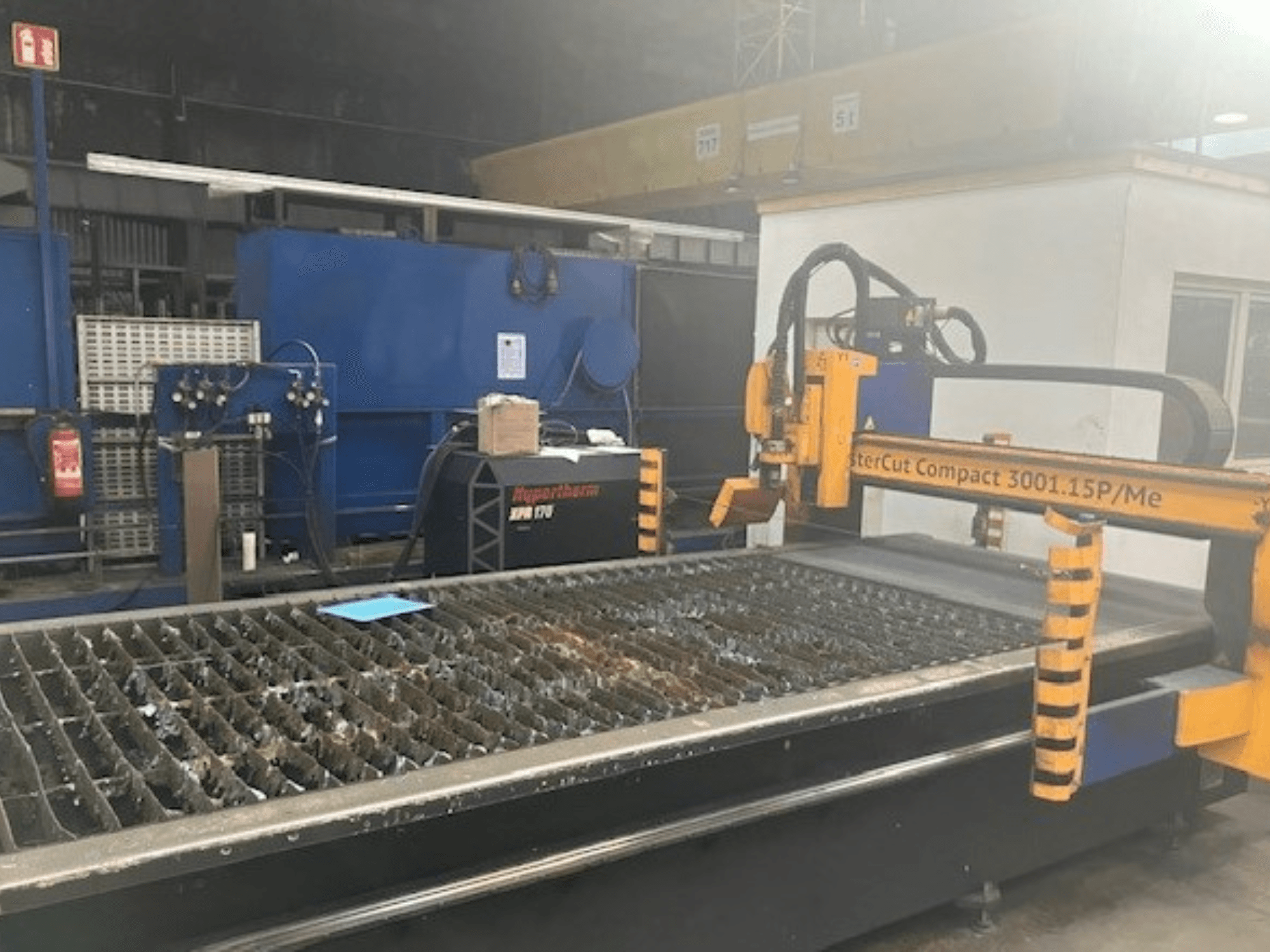 Stroj za plazma rezanje Hypertherm MasterCut Compact 3001.15P/Me u bočnom pogledu, s prikazom stola za rezanje i upravljačke ploče.