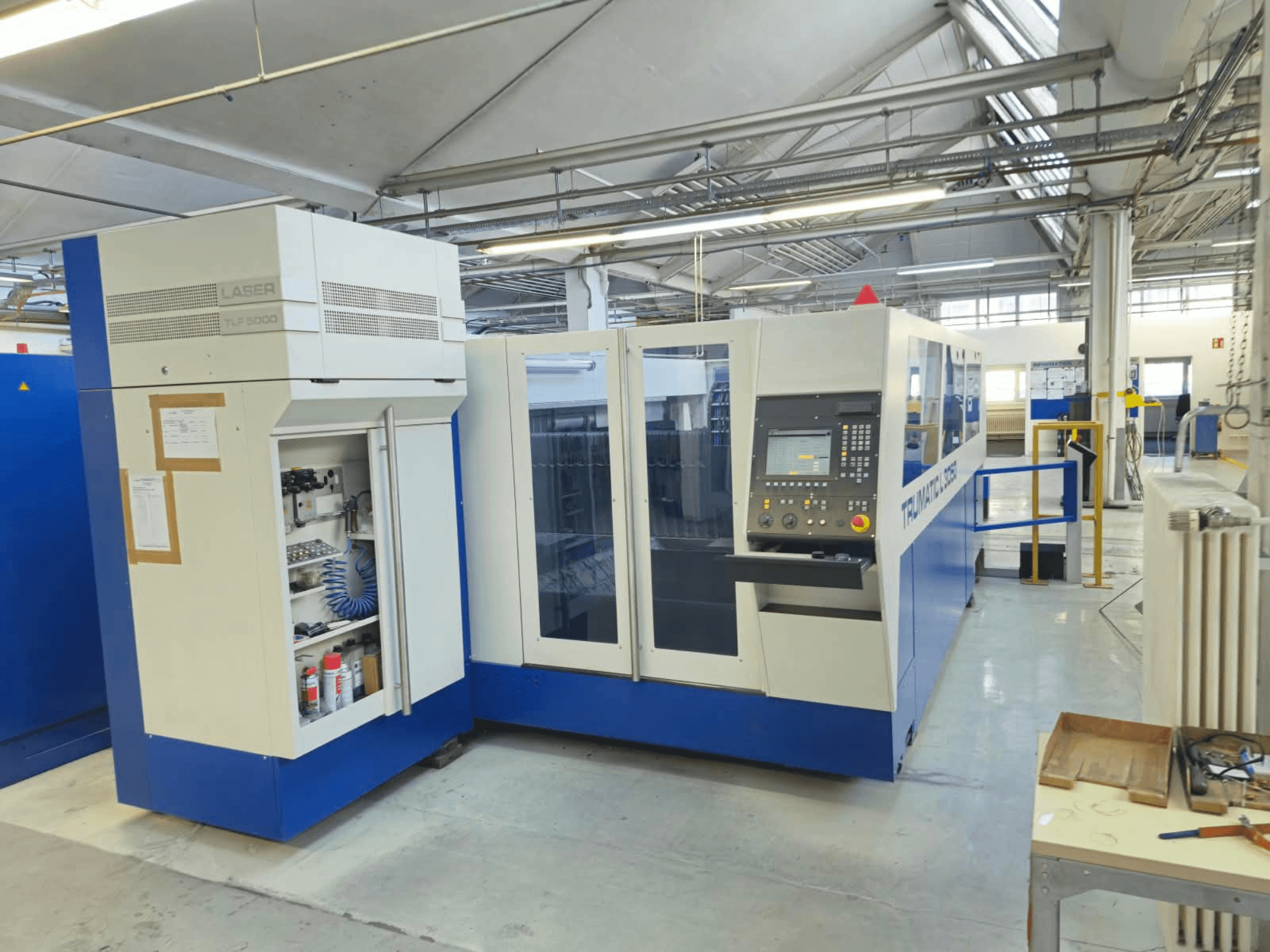 TRUMPF TruLaser L3050 CO2 laserski stroj za rezanje, pogled sprijeda, s upravljačkom pločom i vratima za održavanje, u tvorničkom okruženju.