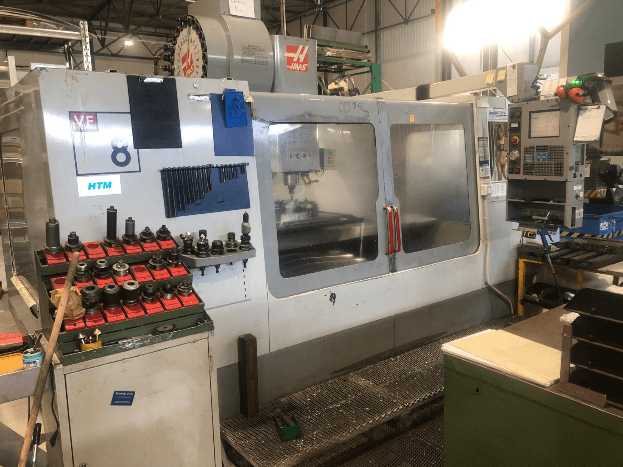 Haas CNC stroj u radionici, pogled sprijeda; prikazuje alate i kontrole, s vidljivim detaljima modela i organiziranim držačima alata.