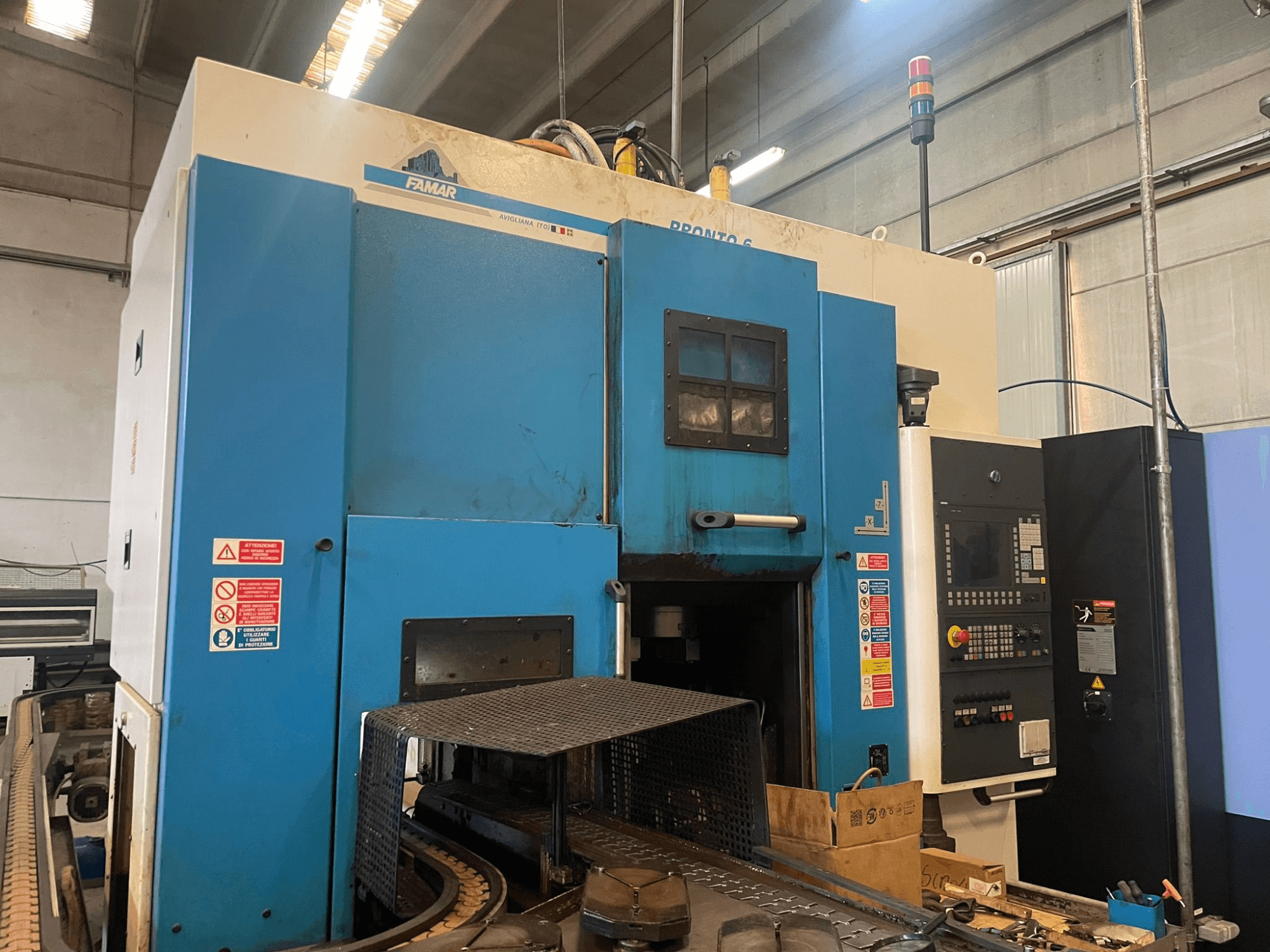 Vertikalna tokarska mašina Famar Pronto 6 u radionici, bočni pogled, prikazuje upravljačku ploču, radne značajke i sigurnosne naljepnice.