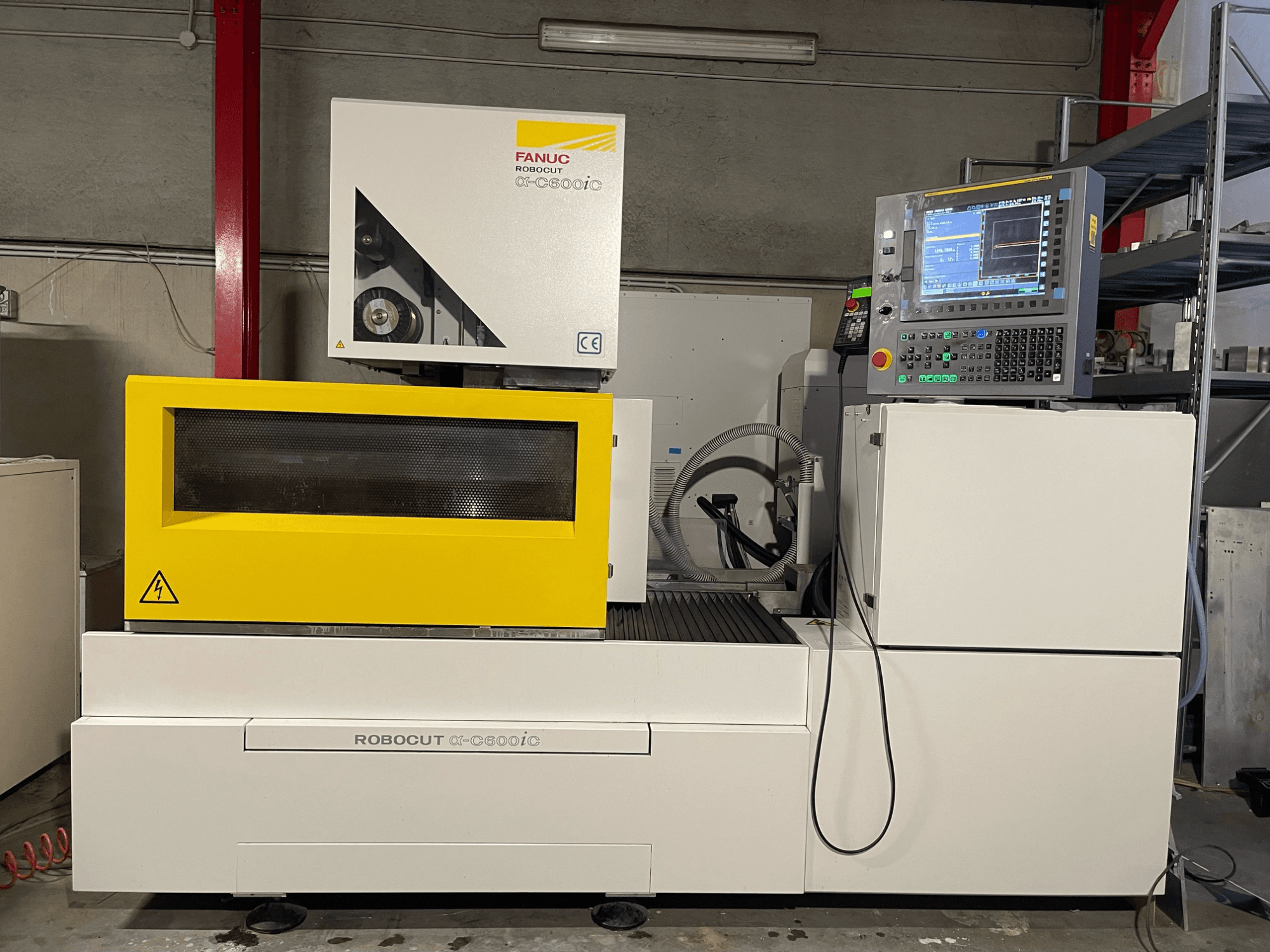 FANUC Robocut α-C600iC, bočni pogled na CNC stroj sa žutim sigurnosnim poklopcem i upravljačkom pločom, koji prikazuje mogućnost preciznog rezanja.