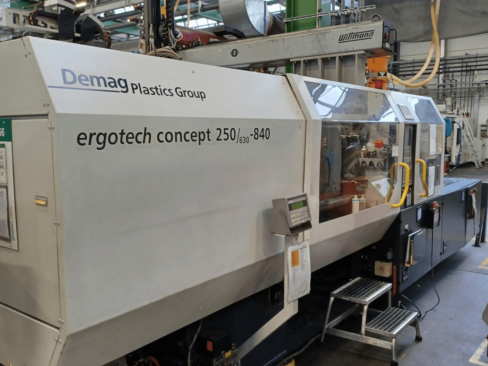 Stroj za brizganje plastike Demag ergotech concept 250/630-840, prednji pogled, s digitalnim kontrolama i prozirnim sigurnosnim poklopcima.
