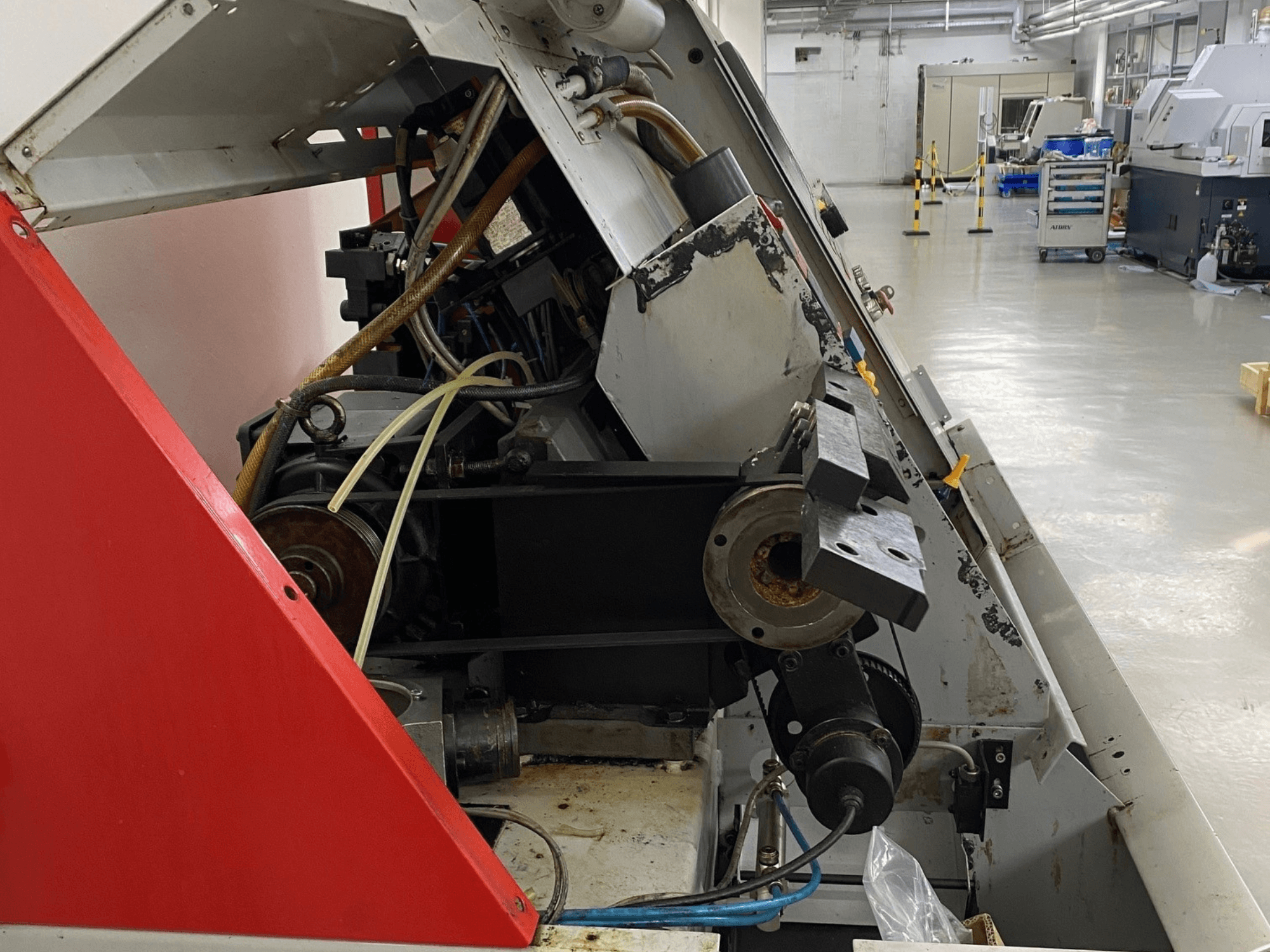 Horizontalni tokarski stroj EMCO Emcoturn 325, bočni pogled koji prikazuje pogonske komponente i hidrauliku u industrijskom okruženju.