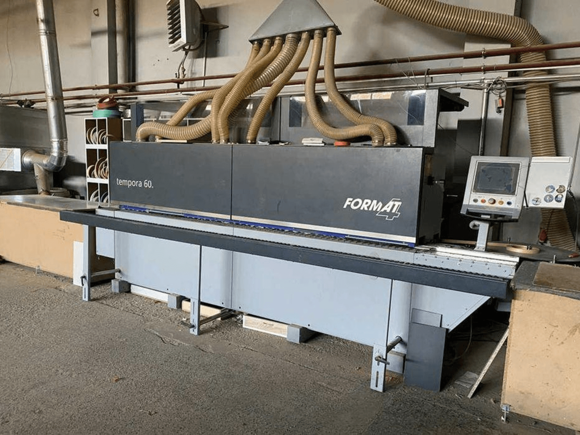 Stroj za lijepljenje rubova FORMAT4 Tempora 60 u bočnom pogledu, s više crijeva i upravljačkom pločom s gumbima i zaslonom.
