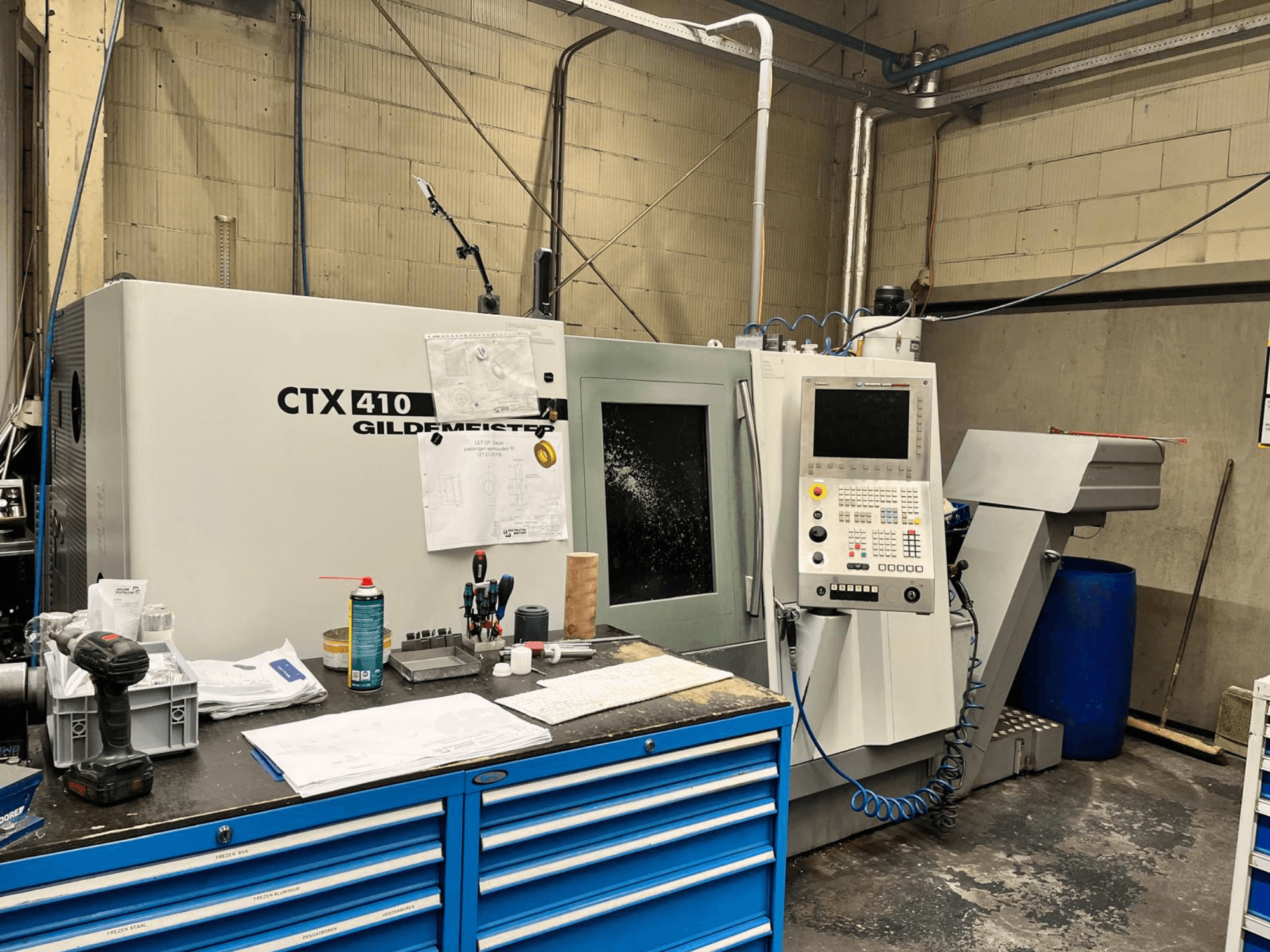 Gildemeister CTX 410 CNC stroj u radionici, prednji pogled, s upravljačkom pločom i raznim alatima na radnom stolu.