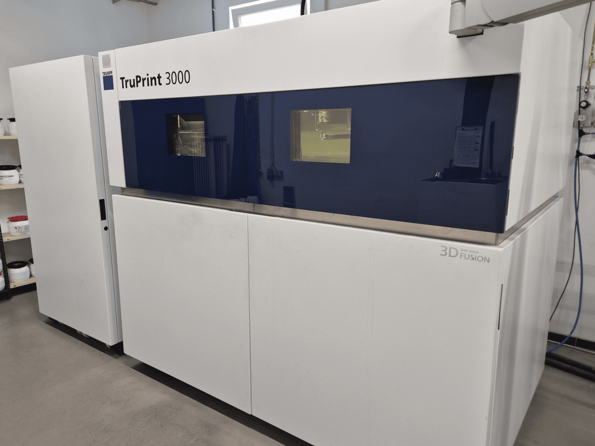 Metalni 3D printer TruPrint 3000 u prednjem pogledu, s dizajnom s plavim panelima i tehnologijom laserske fuzije.