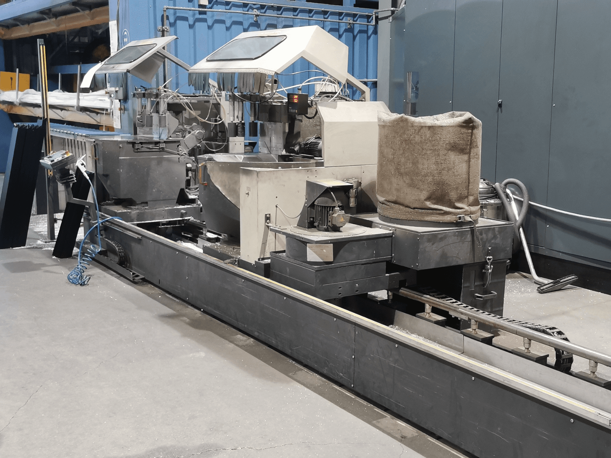 Industrijski stroj za obradu gledan sa strane, s lijevcima, transportnom trakom i upravljačkom pločom, u tvorničkom okruženju.