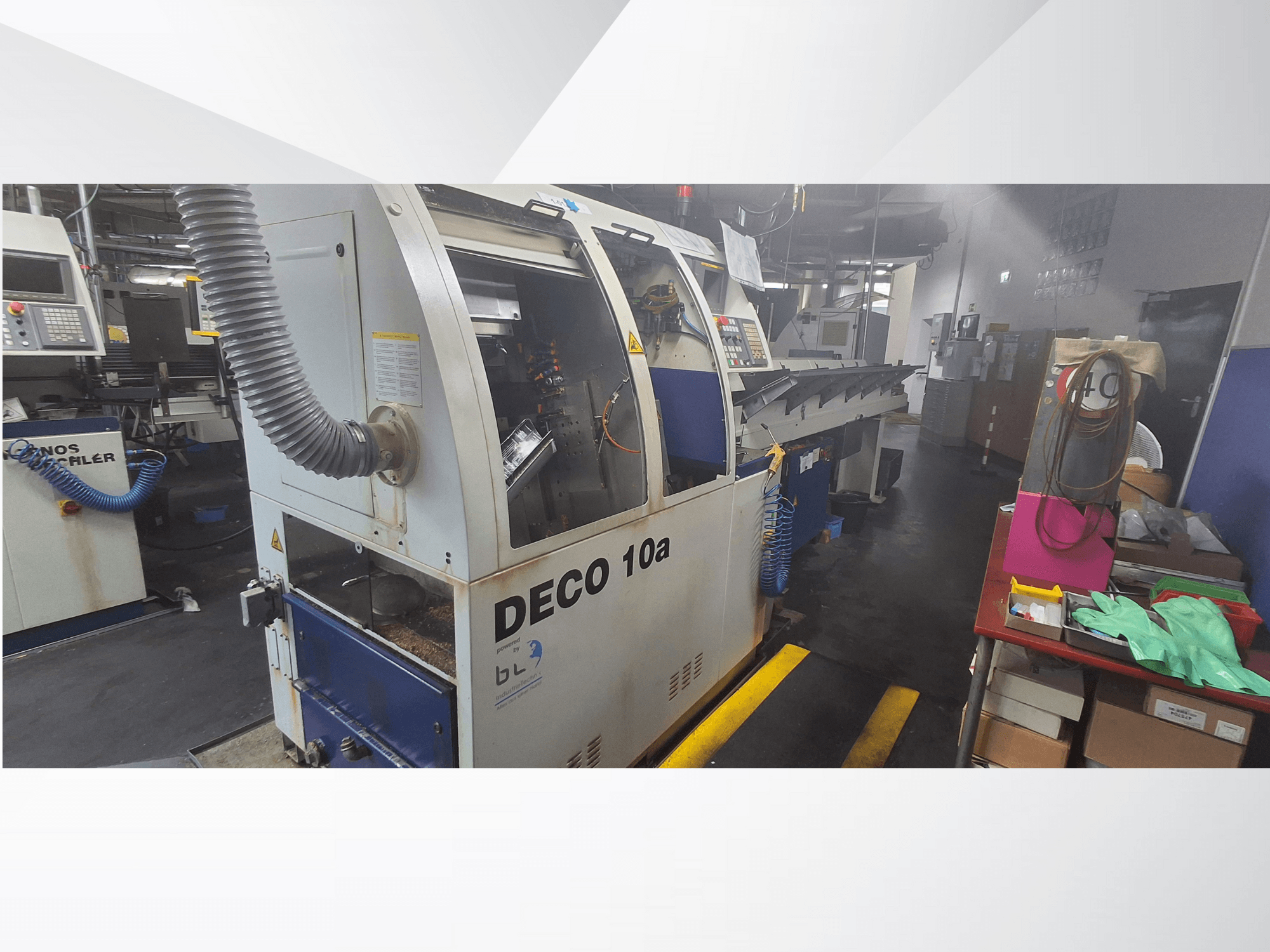 DECO 10a CNC stroj u radionici, pogled sprijeda; ima upravljačku ploču i sustav za usisavanje prašine, s radnim stolom u blizini.